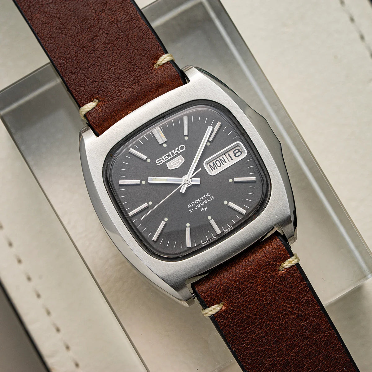 Seiko 5 Baby Monaco ref. 7019-5000 from 1975, dark charcoal dial with 21 jewels printing, squared stainless steel case and brown leather strap