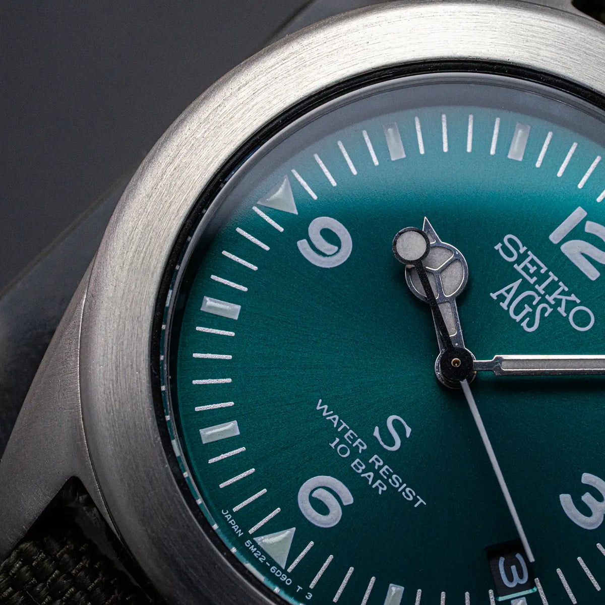 Close-up of the teal Seiko SUS AGS 5M22-6C30 dial with Arabic markers and date display