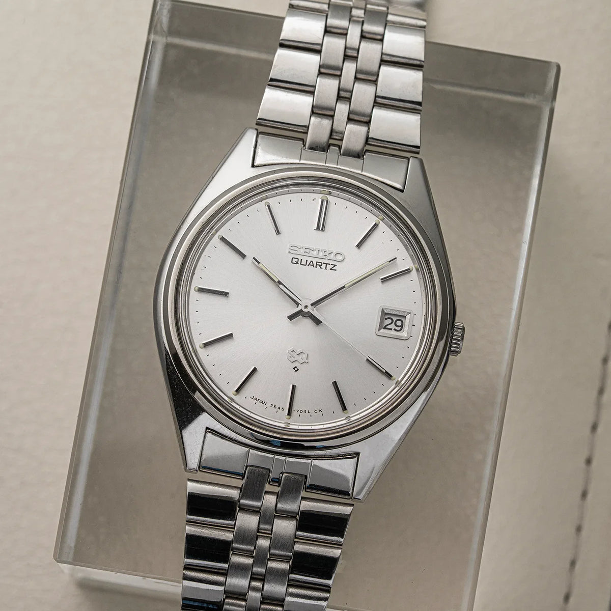 Seiko SQ 7545-7030 from 1979, silver analog dial with SQ emblem and date, shown on its original steel bracelet