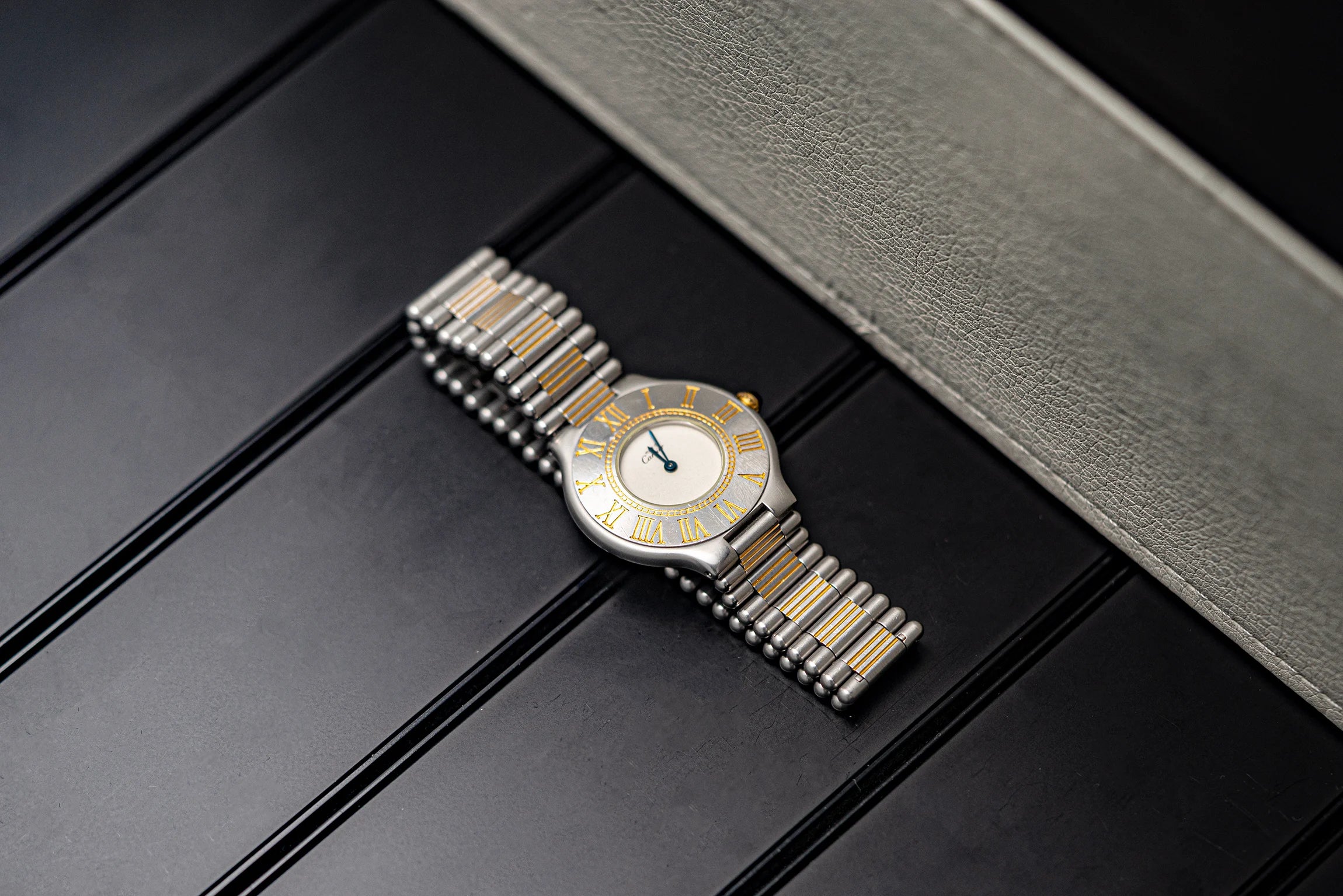 Silver and gold Cartier Must De Cartier 21, Ref. 9010, Cal. 81, 1989 watch on a dark surface with a gray textured background
