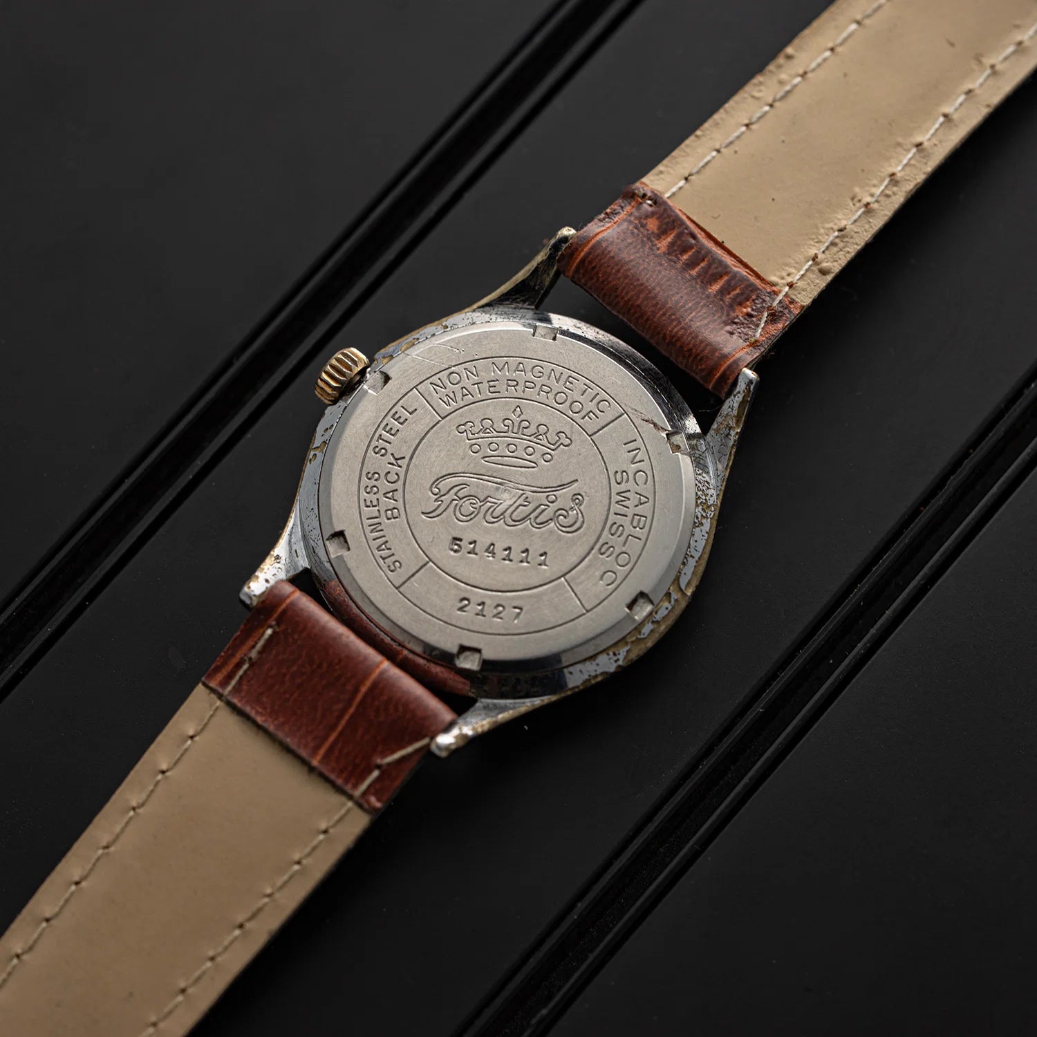 Fortis, Ref. 2127, Cal. ETA 1080, Men’s Manual Wind, 1958 caseback with brown leather strap on a black background