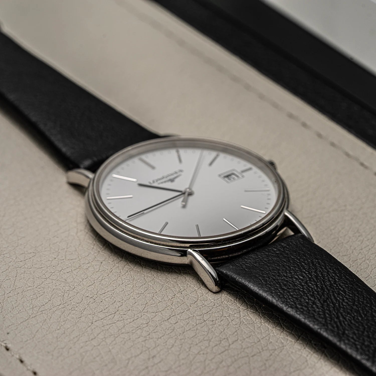 Wristwatch Longines Presence, Ref. L4.790.4, Cal. L157.2, 2018 with black strap and silver case on a textured surface