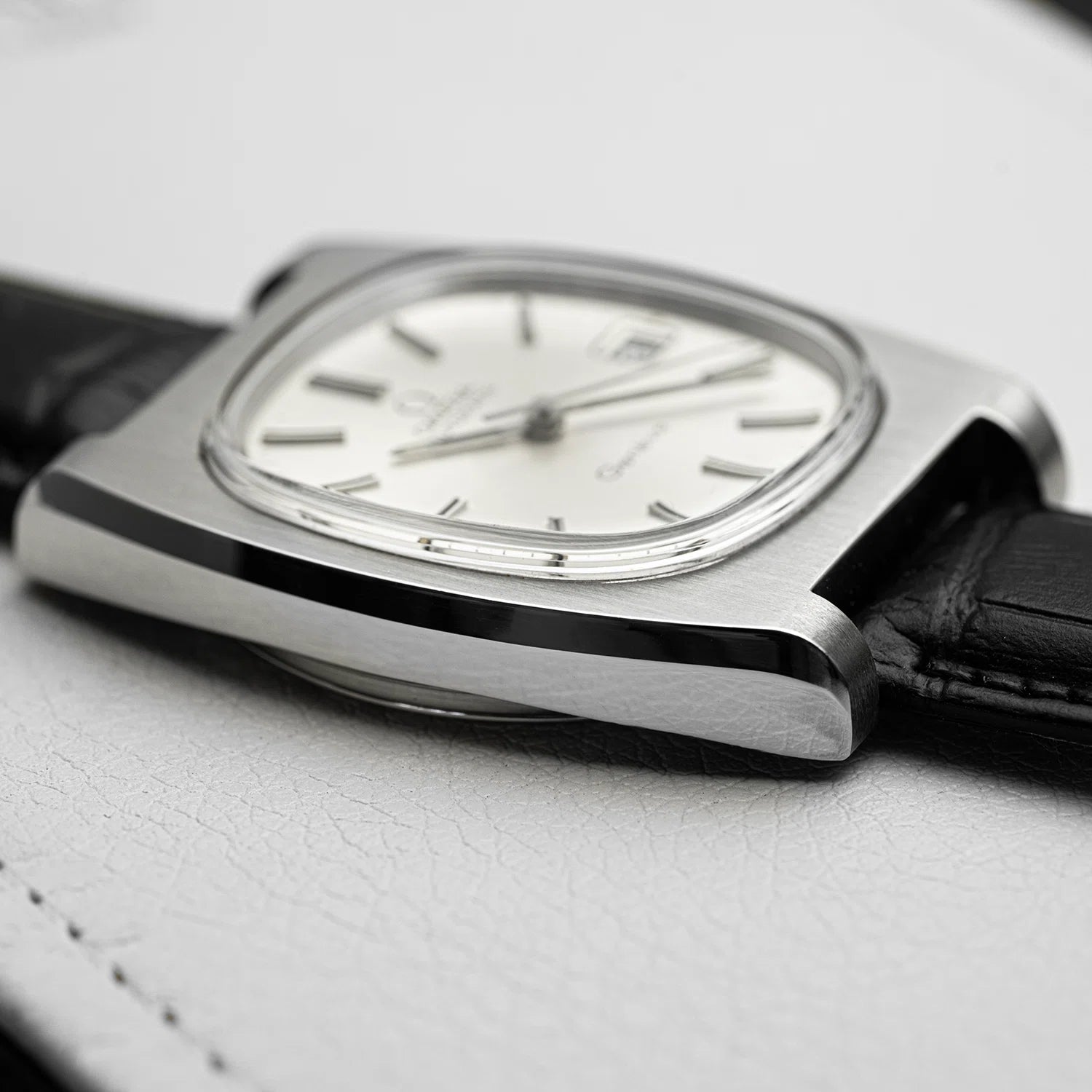Watch with black strap and silver case on a light gray background