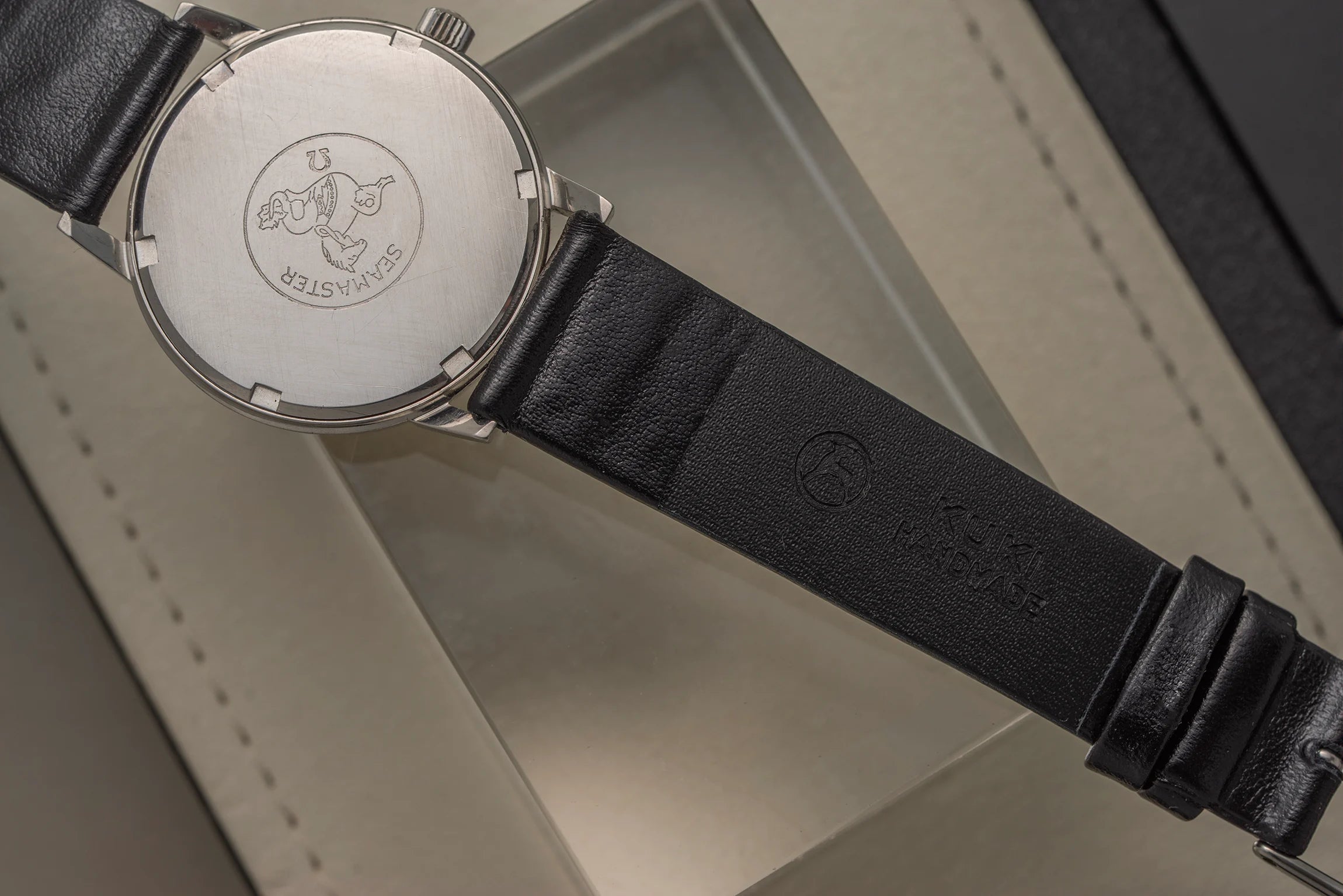 Close-up of a watch Omega Seamaster 600, Ref. 136.011, Cal. 611, 1966 with a black leather strap on a neutral background