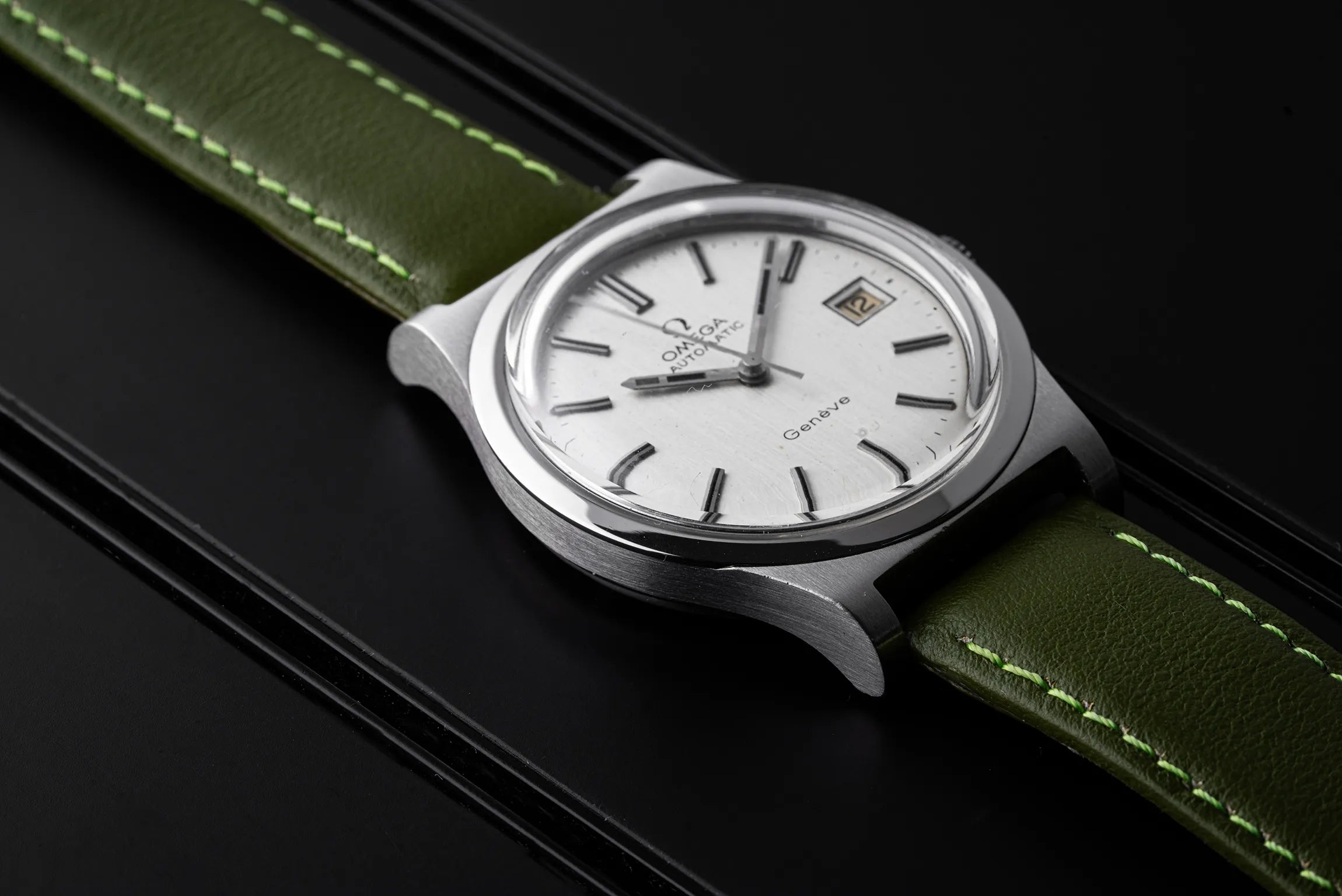 Omega Genève, Ref. 166.0168, Cal. 1012 with green strap and silver case on a black background