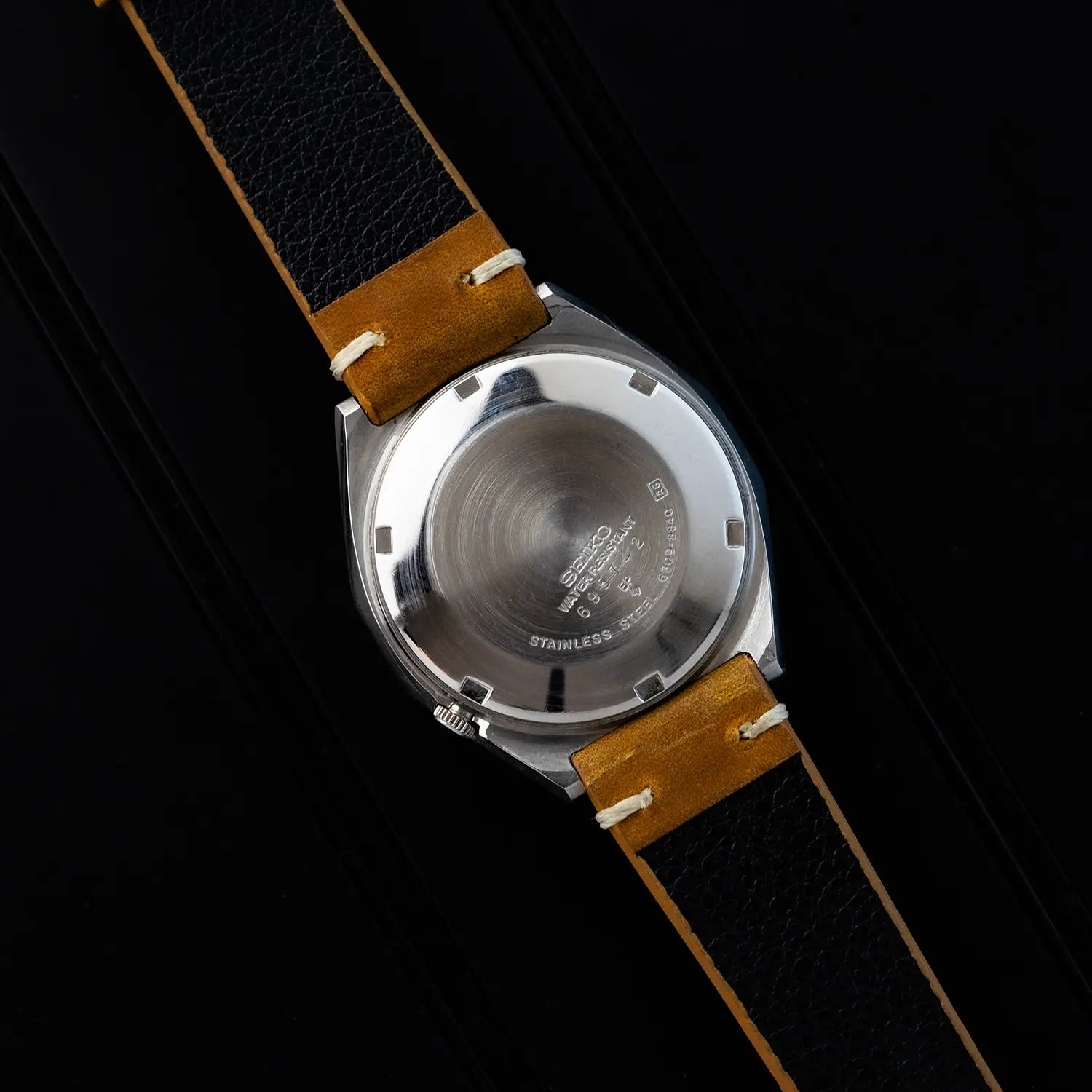 Seiko 5 6309 8840 caseback with brand logo on a black background