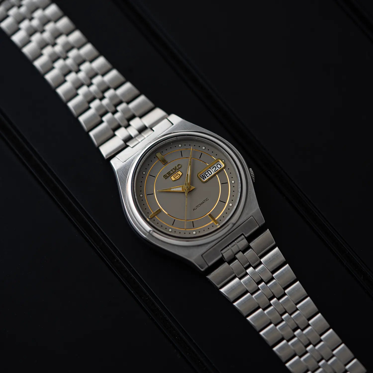 Silver Seiko 5 7S26 3170 watch with a detailed face on a black background