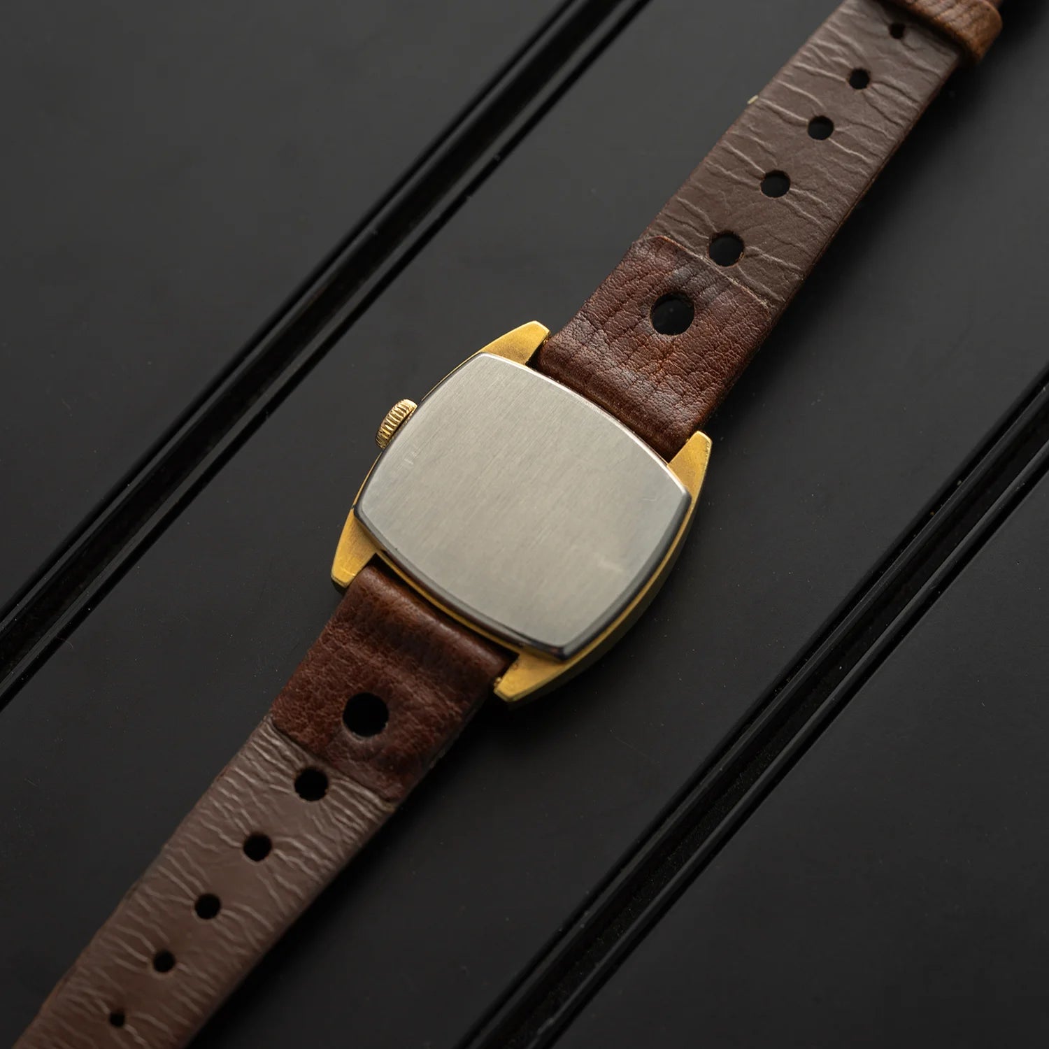 Caseback of Tissot vintage women’s dress watch with brushed steel back and brown leather strap