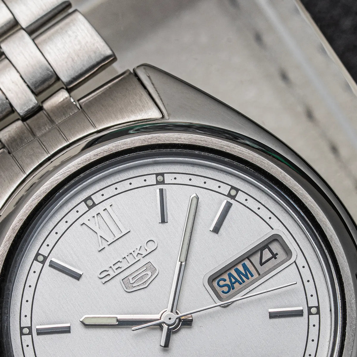 Close-up of a SSeiko 5, Ref. 7009-3140, Cal. 7009, Men’s Automatic, 1979 stainless steel watch with a silver dial, Roman numeral XII, baton hour markers, and a day-date window showing SAM 4.