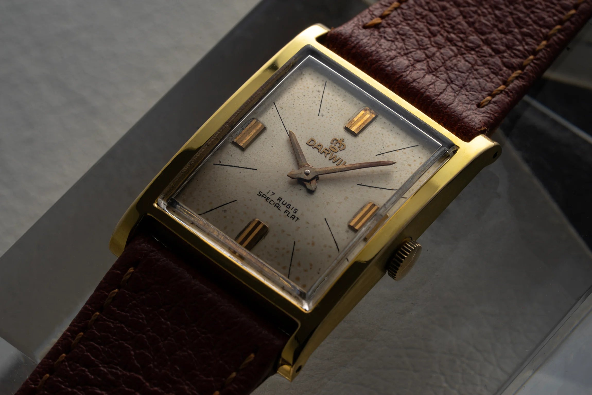 Close-up of Darwil Special Flat dial with patina, applied gold-tone hour markers, and rectangular gold plated case