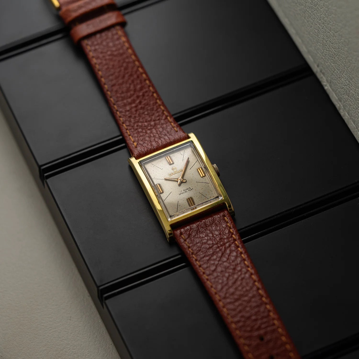 Side angle of Darwil Special Flat watch with slim rectangular gold plated case and brown leather strap