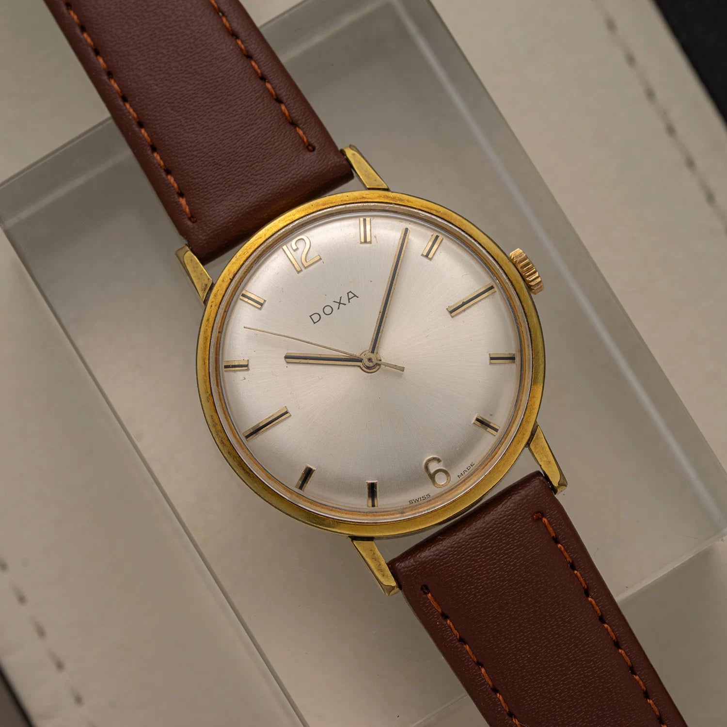 Doxa, Ref. 10346-5, Cal. 103, Men’s Manual Wind, 1970 with brown leather strap on a gray surface