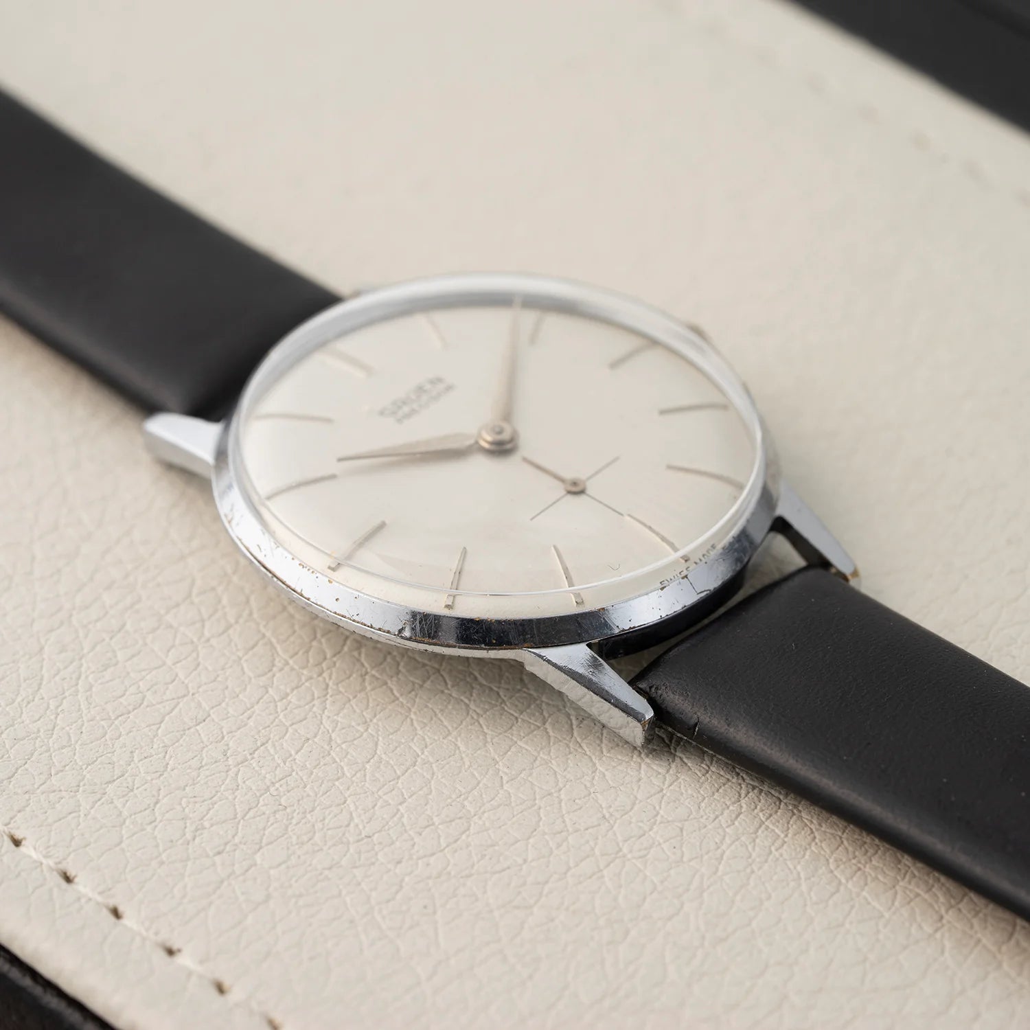 Side profile of Gruen Precision vintage dress watch with slim round case, long lugs, and black leather strap