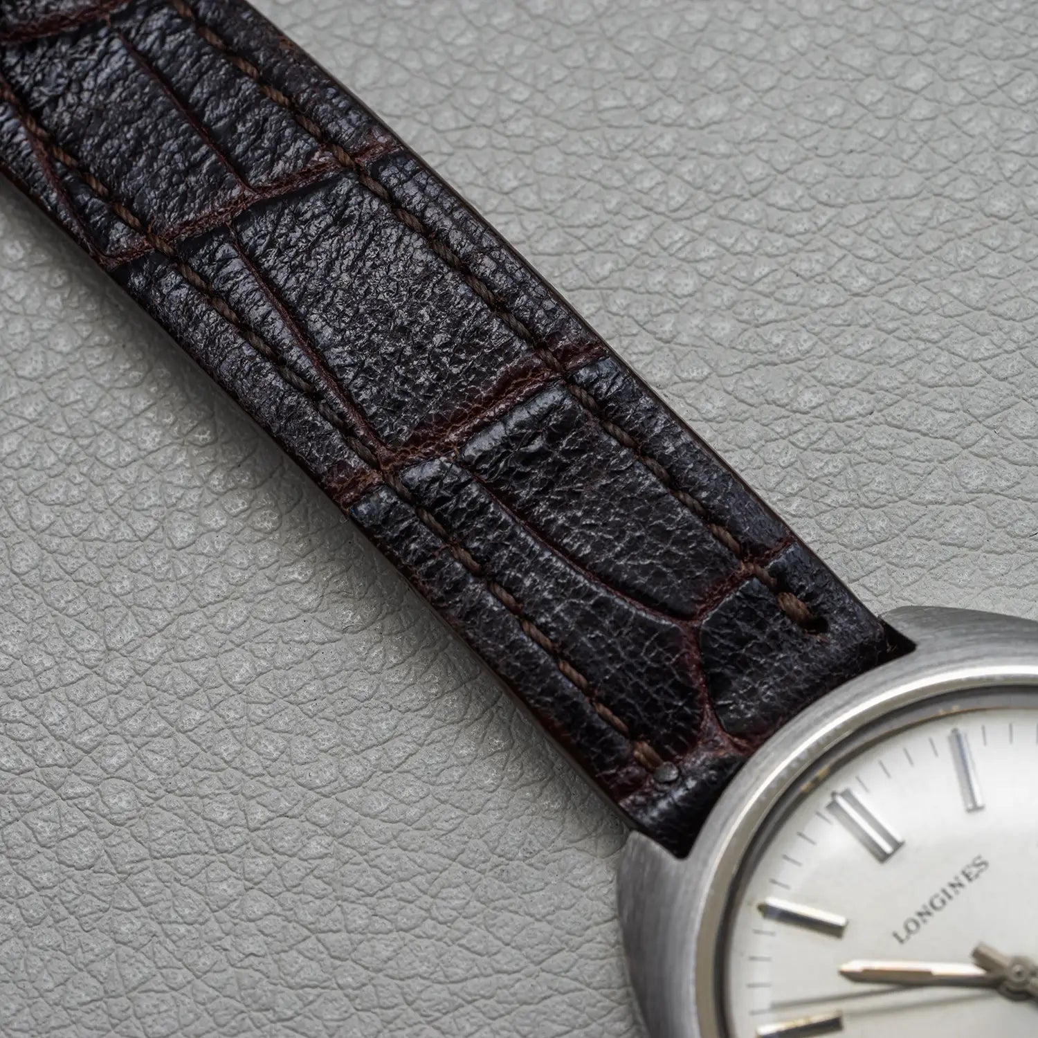 Watch with a brown leather strap on a gray textured background
