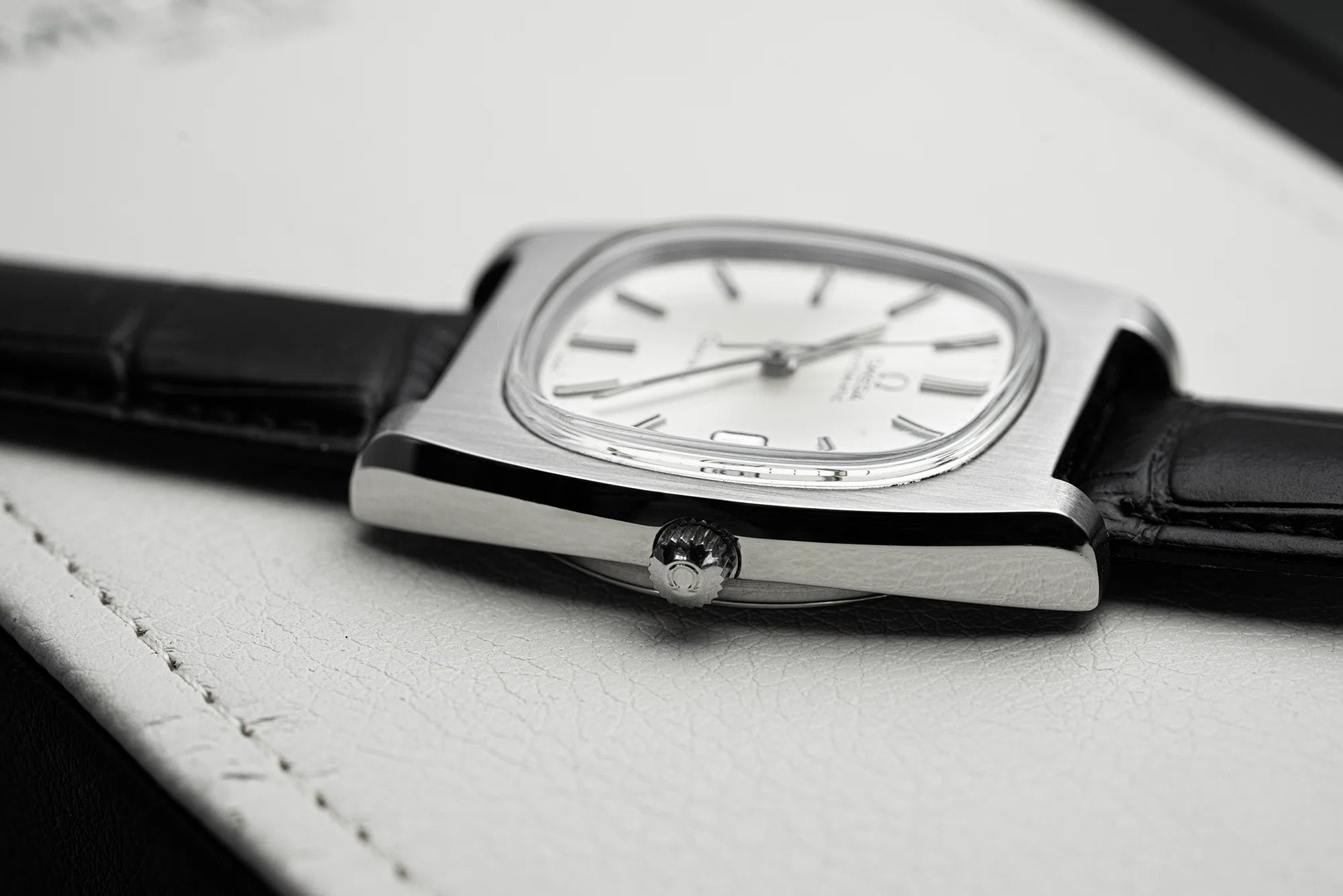 Vintage Omega Geneve watch with Reference 166.0190 and 1012 Caliber with a black leather strap on a light gray surface showing signed Omega logo