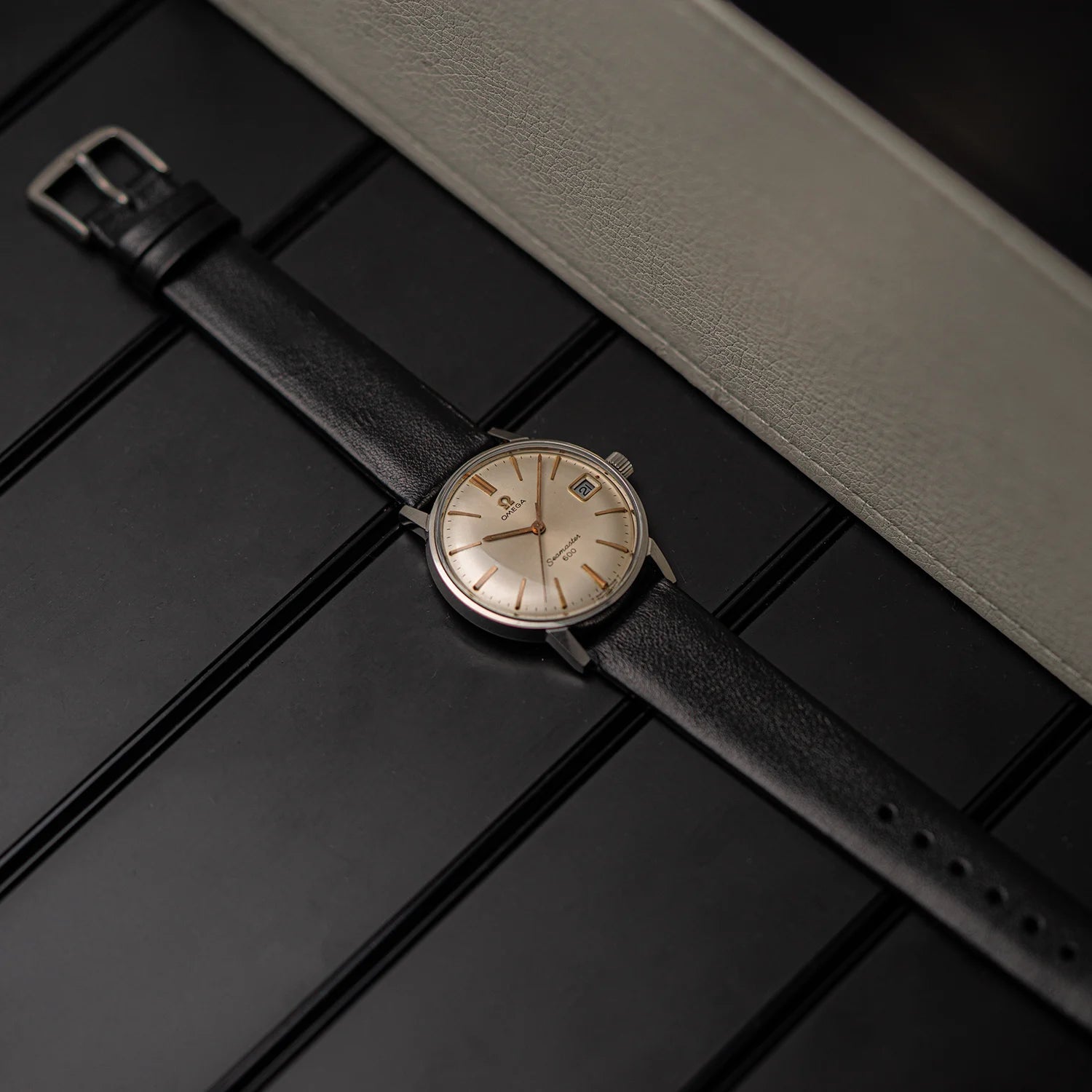 Vintage wristwatch Omega Seamaster 600, Ref. 136.011, Cal. 611, 1966 with black strap on a dark surface