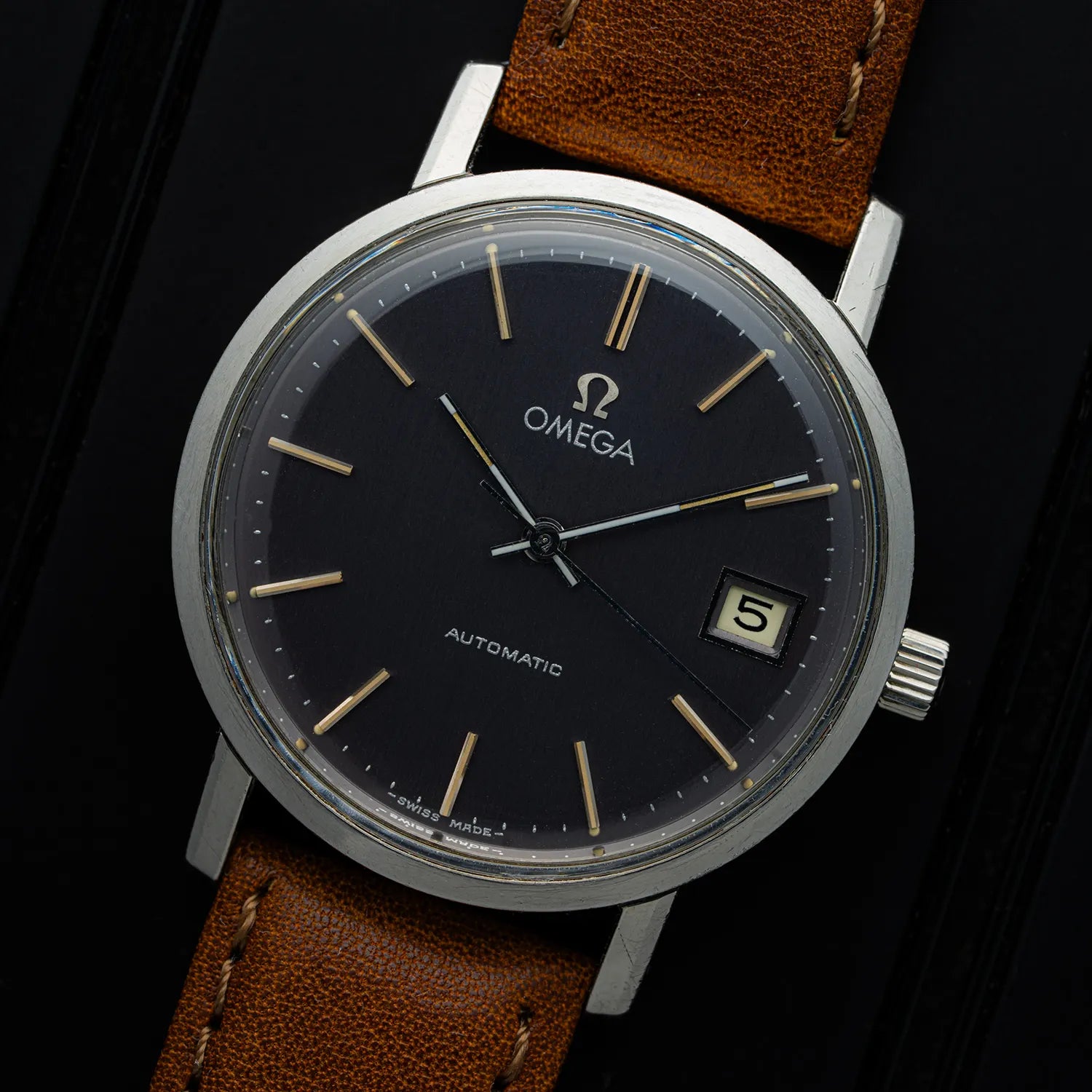 Omega 166.0202, Cal. 552 watch with Charchoal dial and brown leather strap on a dark background