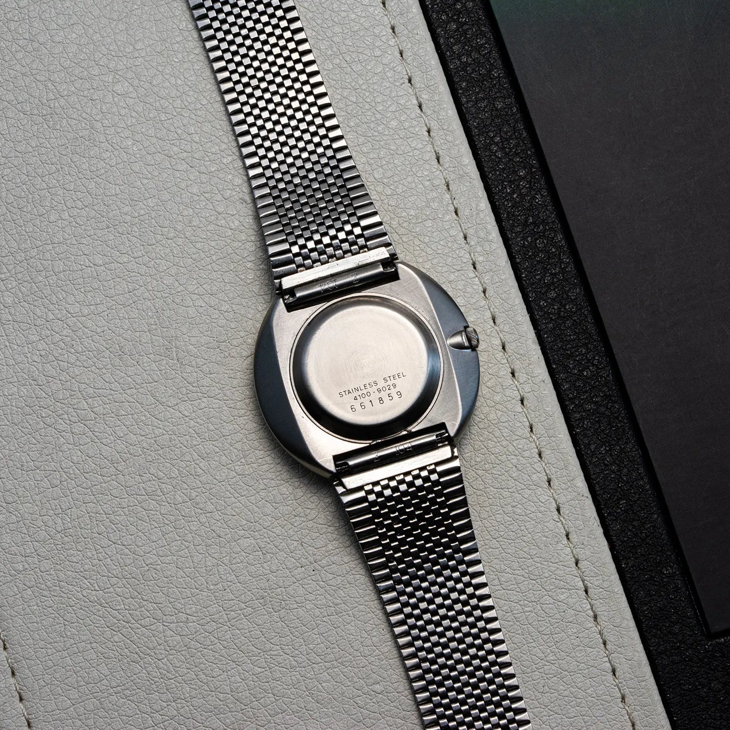 Silver Seiko Quartz 4100-9029 with mesh band on a gray textured surface