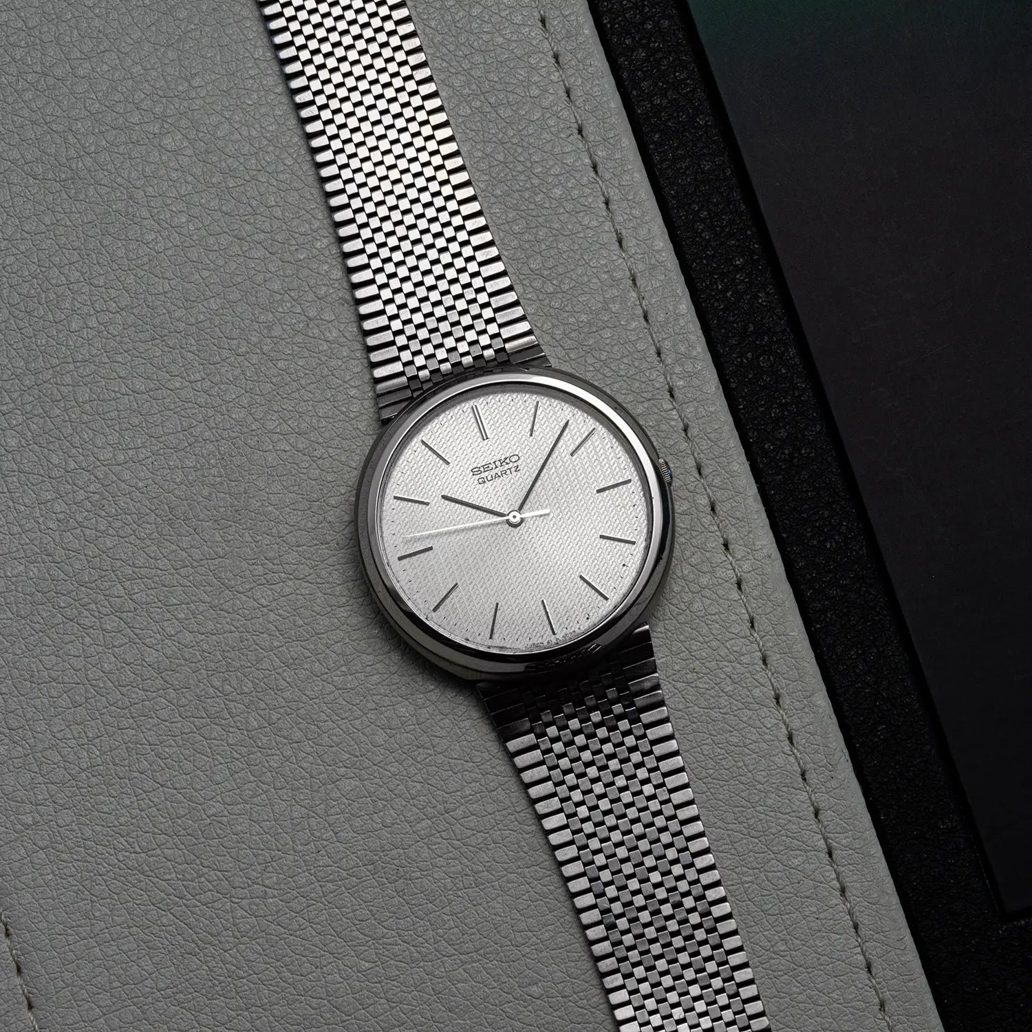 Wristwatch Seiko Quartz 4100-9029 with silver bracelet on a gray textured surface