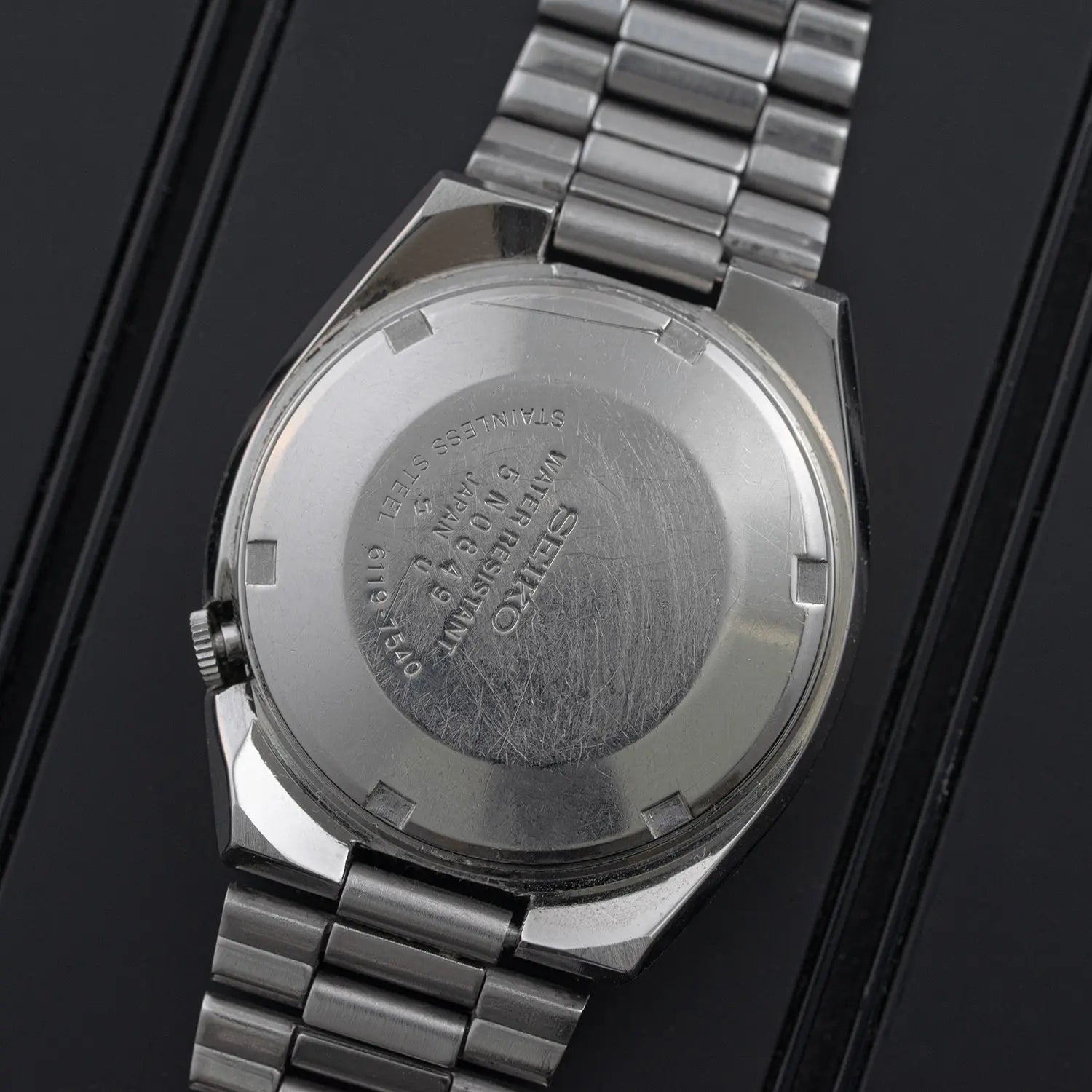 Close-up of a Seiko 5 6119 7540 with brand engraving on a black background