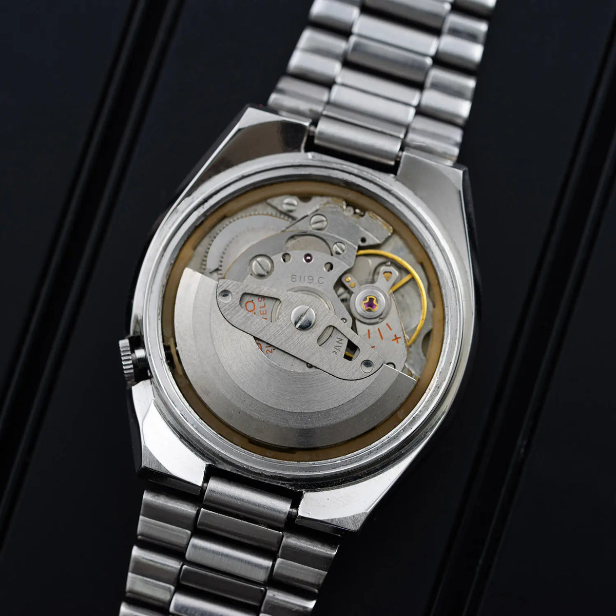 Open caseback of a Seiko 5 6119-7540 showing the rotor, balance assembly and the stamped Seiko 6119C caliber