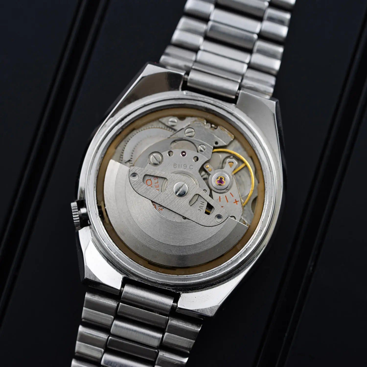 Close-up of a silver watch with visible mechanical components on a black background