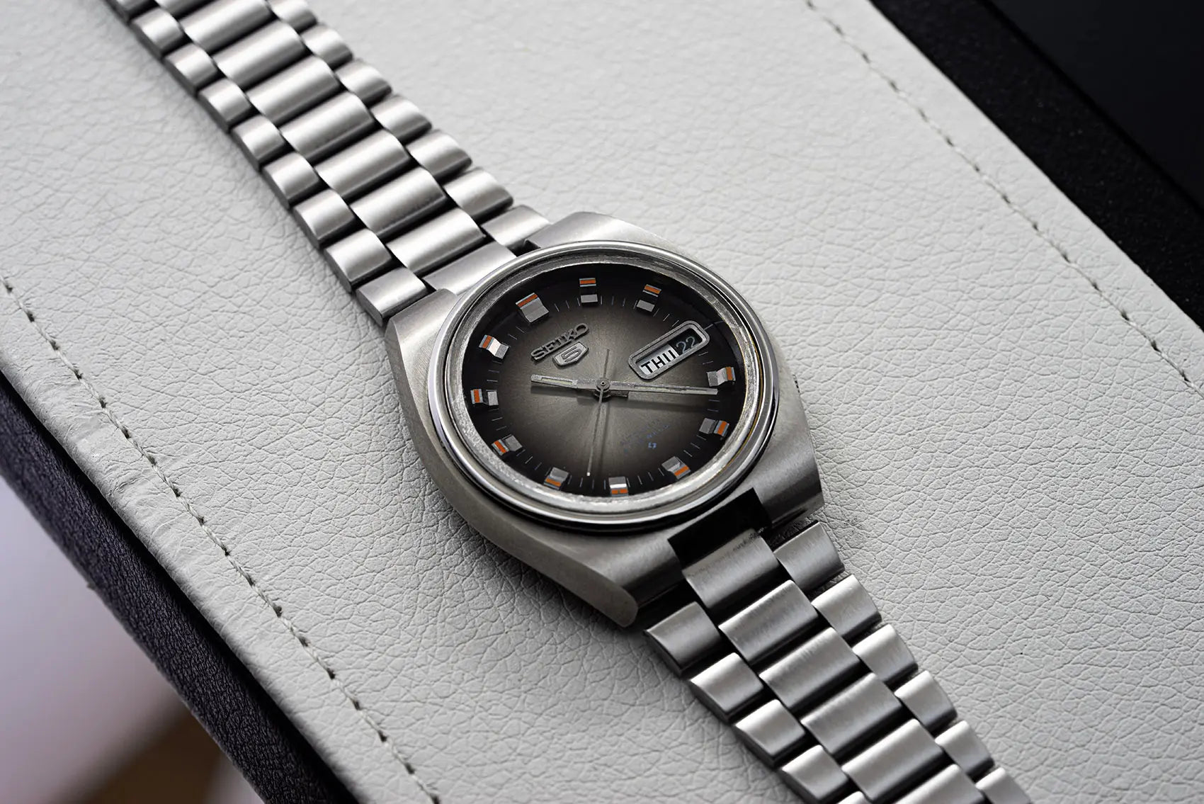 Seiko 5 6119 7540 with a black face on a light gray background