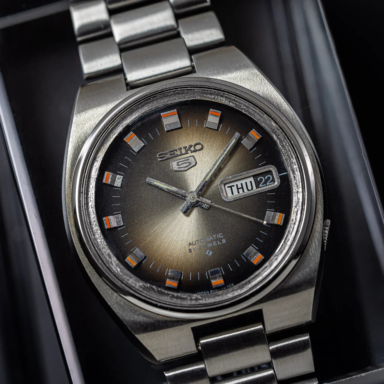 Silver Seiko 5 6119 7540 watch with a dark face on a black background