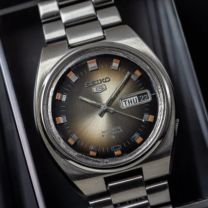 Silver Seiko 5 6119 7540 watch with a dark face on a black background