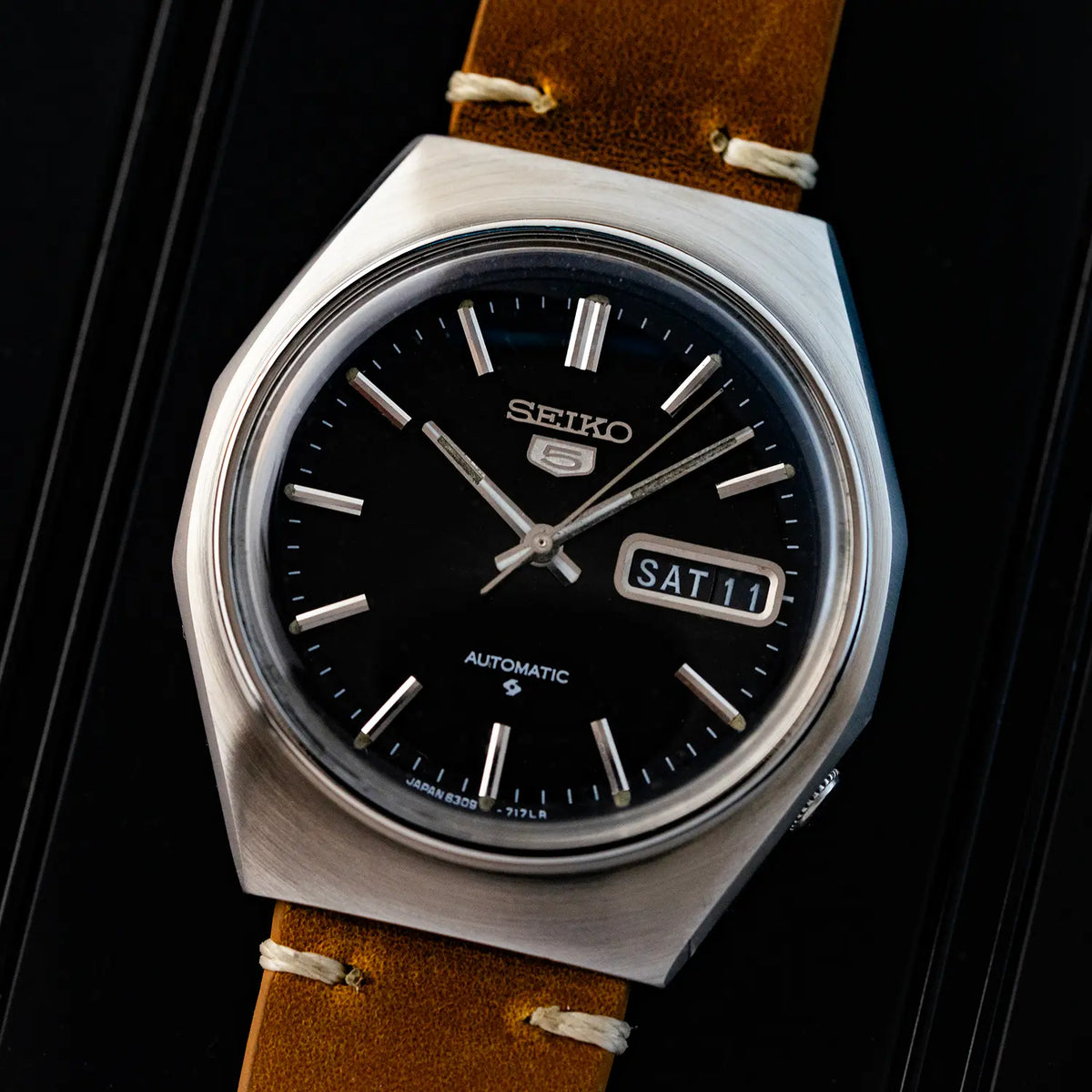 Seiko 5 6309 8840 watch with black dial and brown leather strap on a dark background