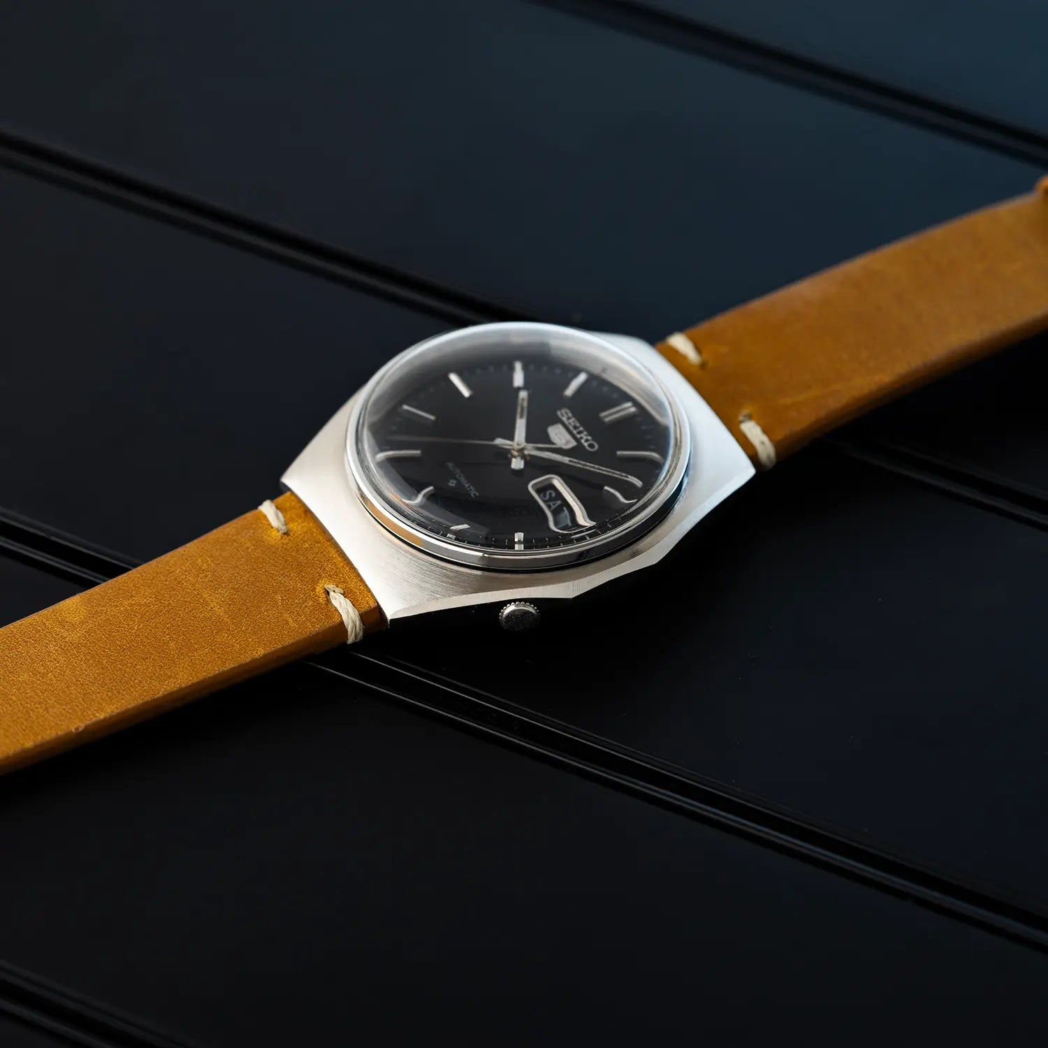 Vintage-style Seiko 5 6309 8840 watch with brown leather strap pointing on case and crown