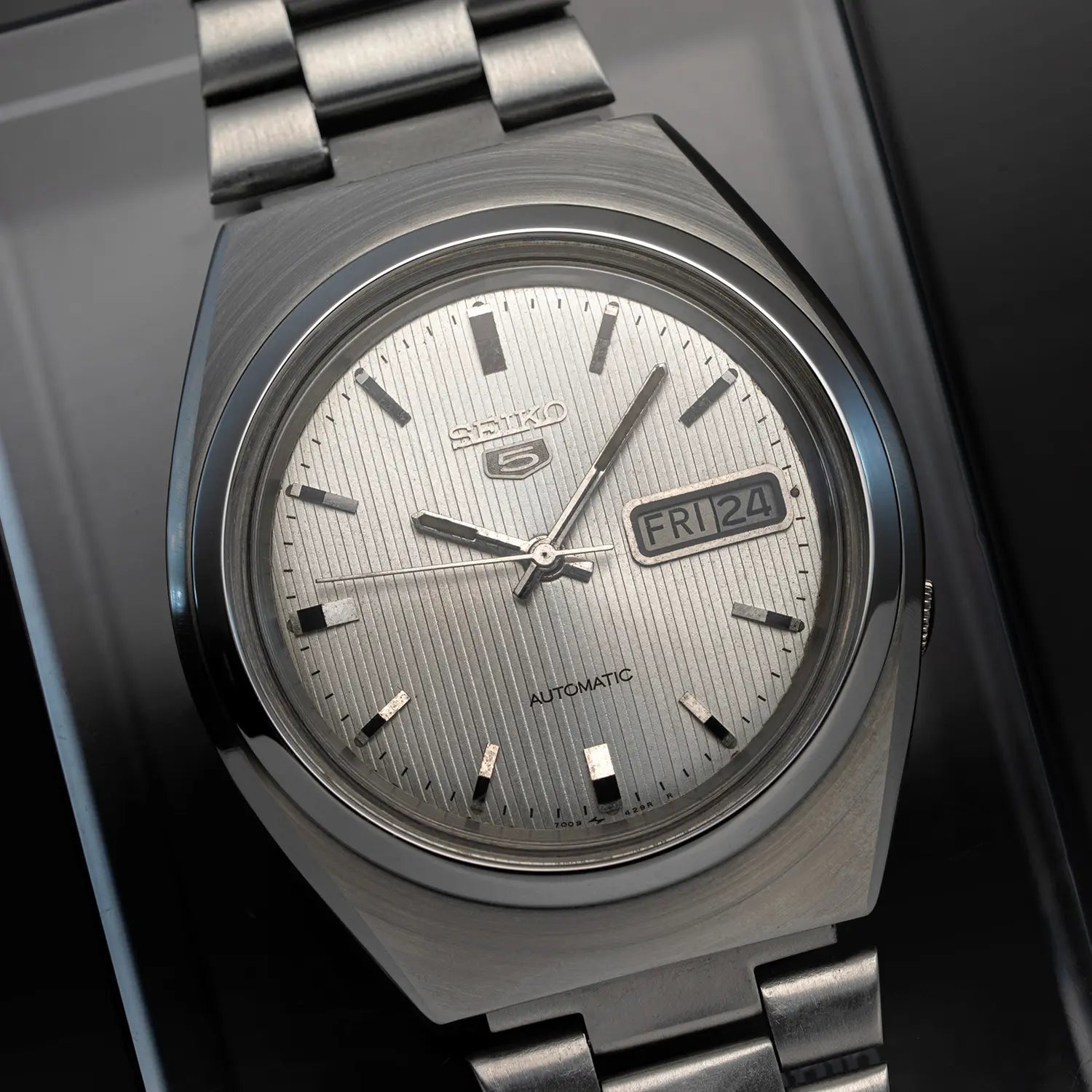 Silver Seiko 5 7009 8431 with a detailed face on a dark background