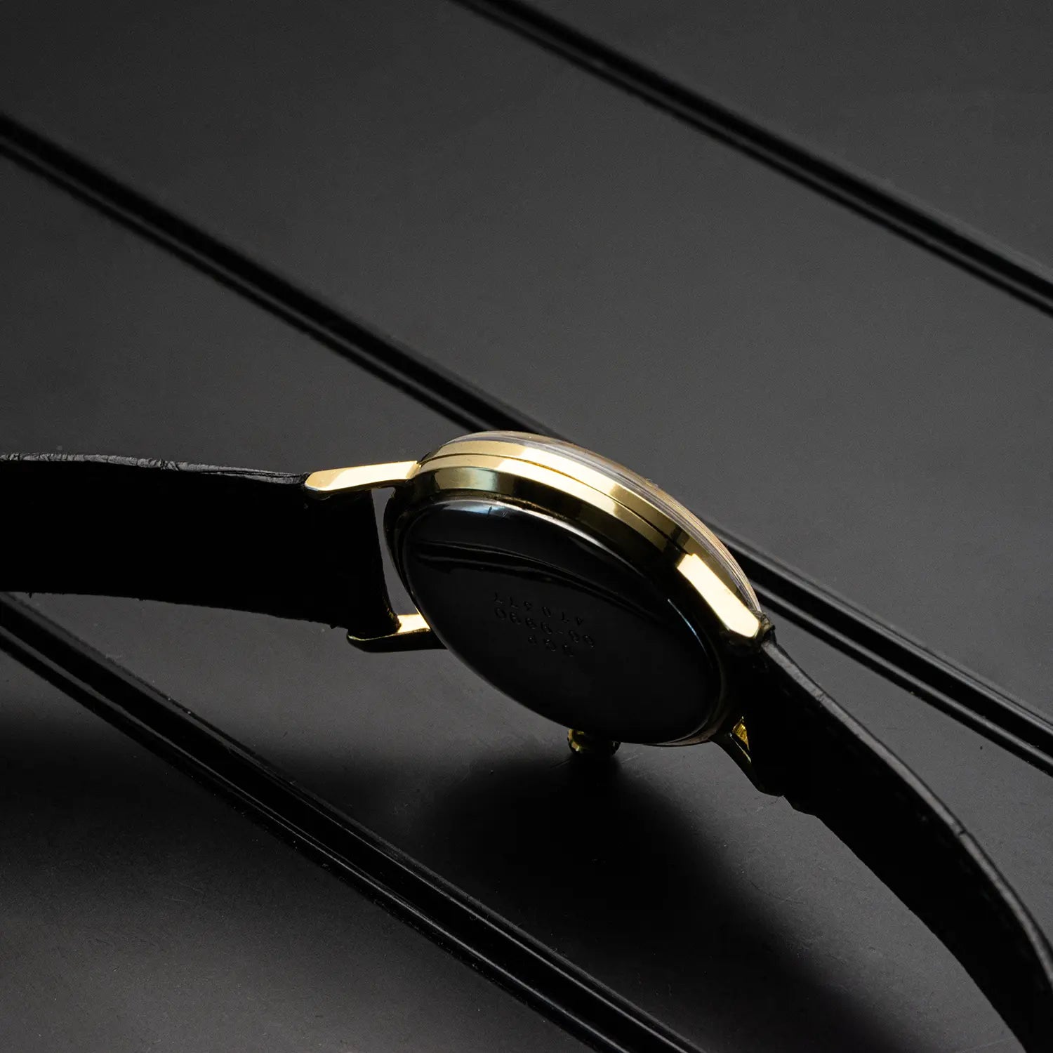 Gold plated watch case of Seiko 66 9990 with black strap on a dark background