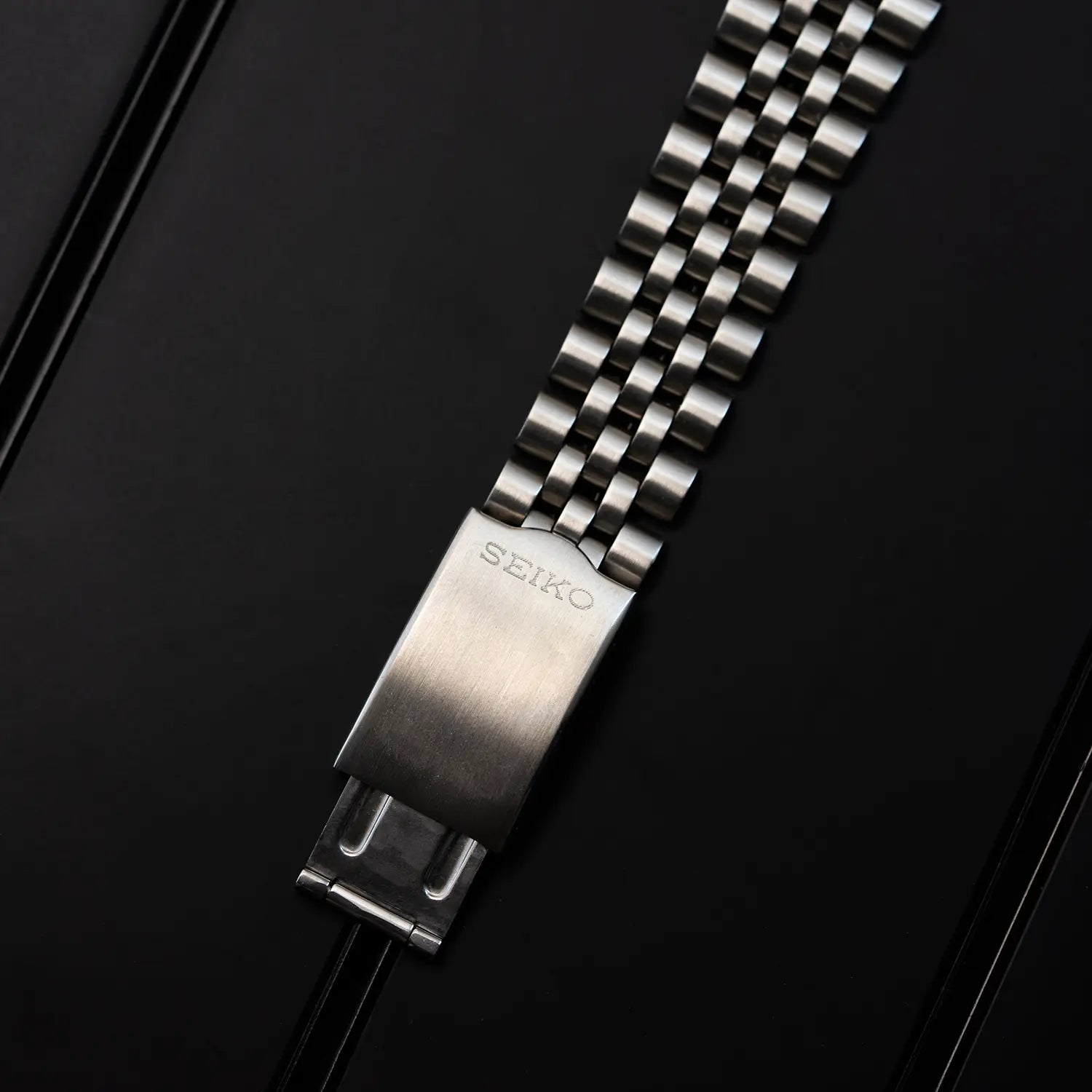 Seiko 5 7009 3040 watch bracelet with Seiko clasp on a black background