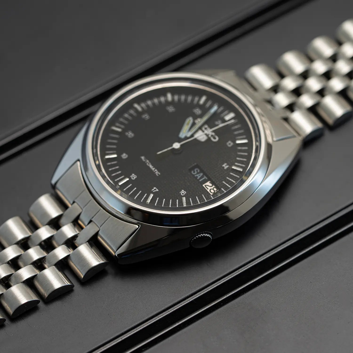 Seiko 5 7009 3040 case with a black dial on a dark background