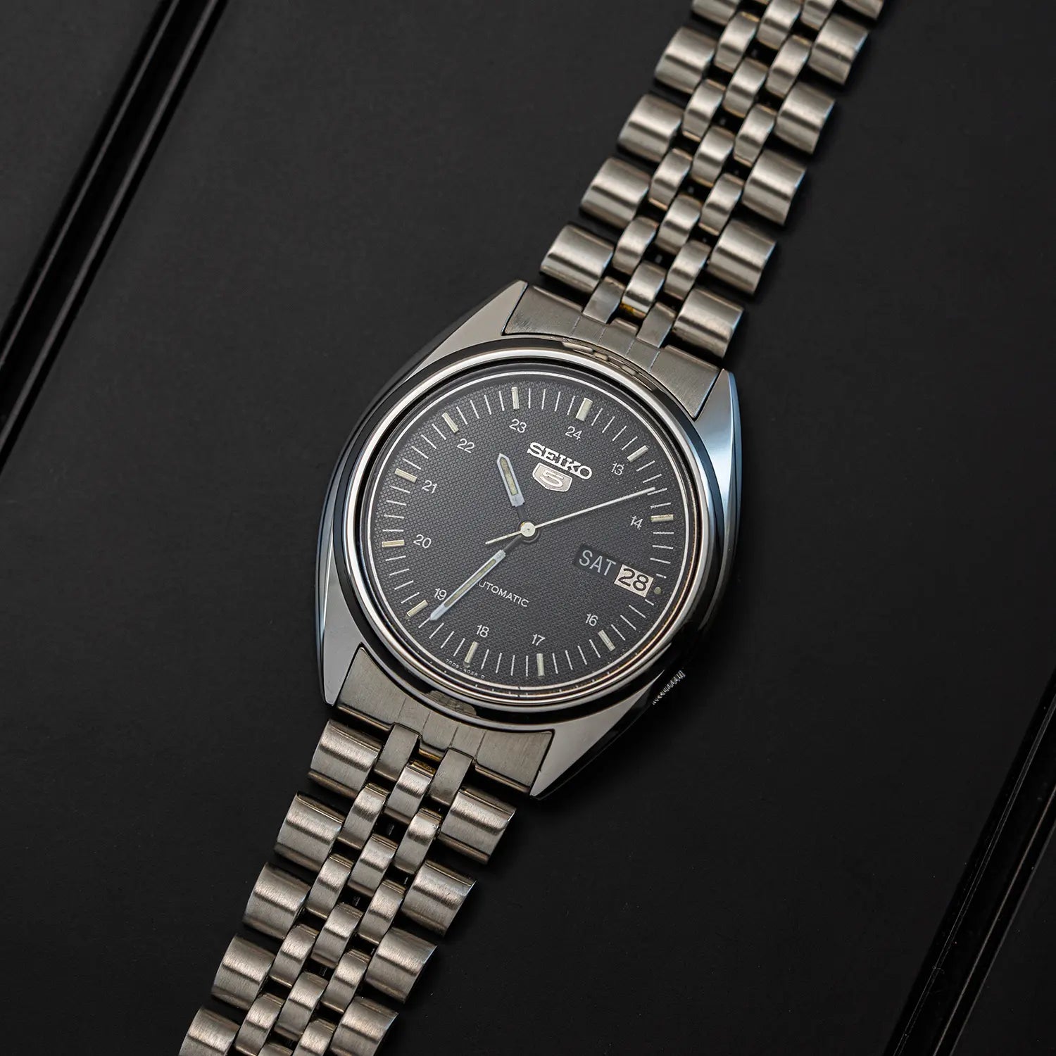 Seiko 5 7009 3040 watch with a black face on a dark background top view