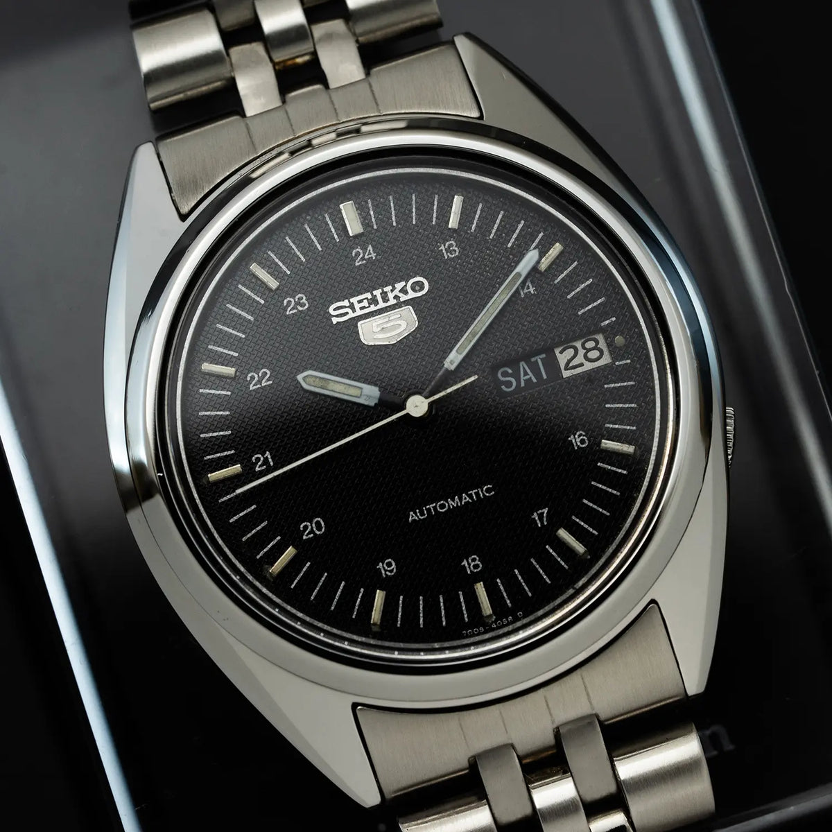 Seiko 5 7009 3040 watch with black dial on a dark background
