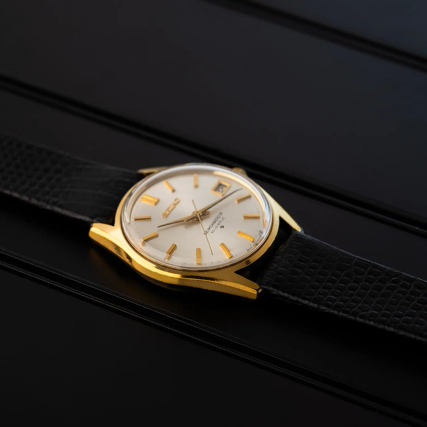 Vintage watch Seiko 8305 8010 with gold case and black strap on a dark background