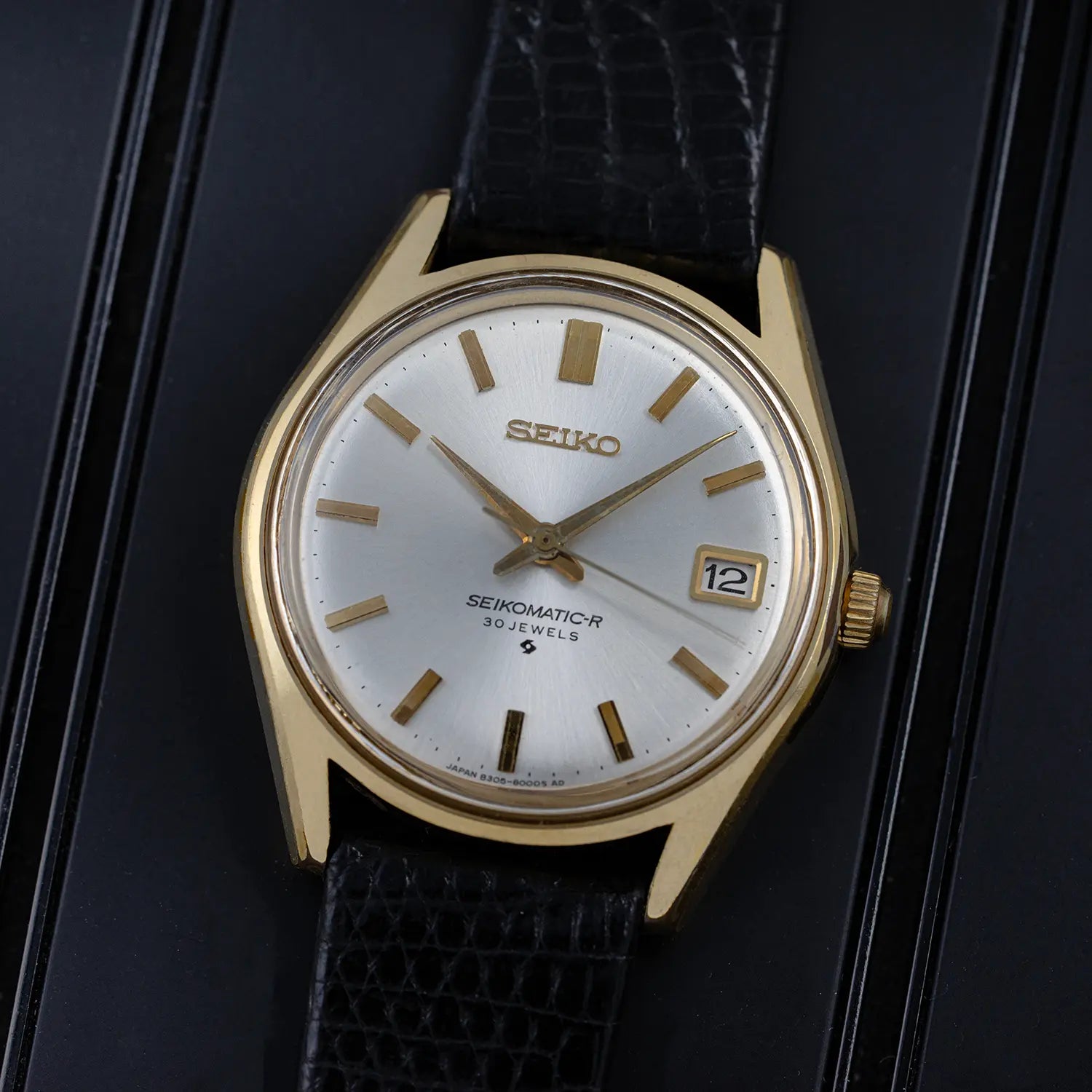 Vintage Seiko 8305 8010 watch with gold case and black leather strap on a dark background
