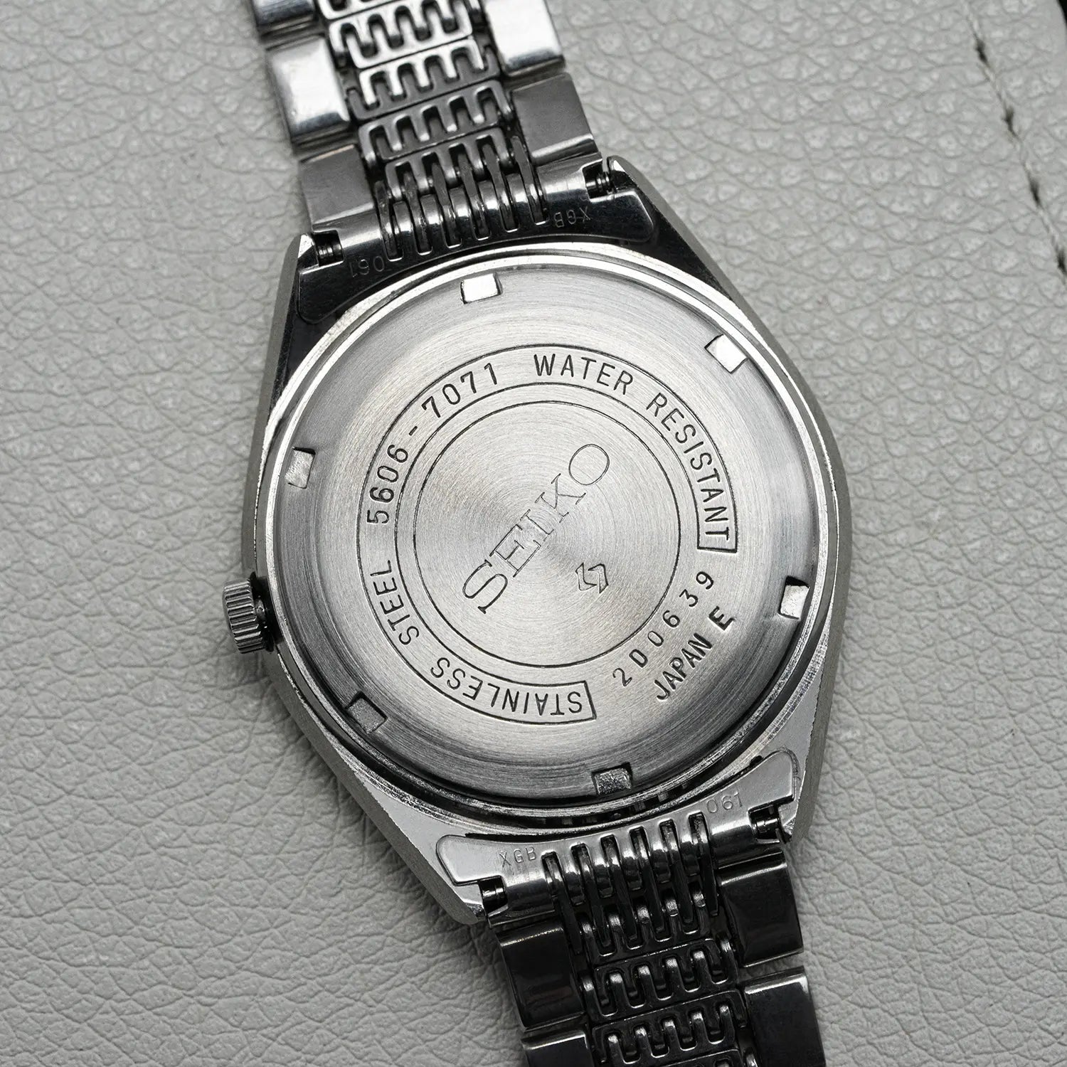 Back view of a Seiko LM 5606-7071 watch on a gray textured background