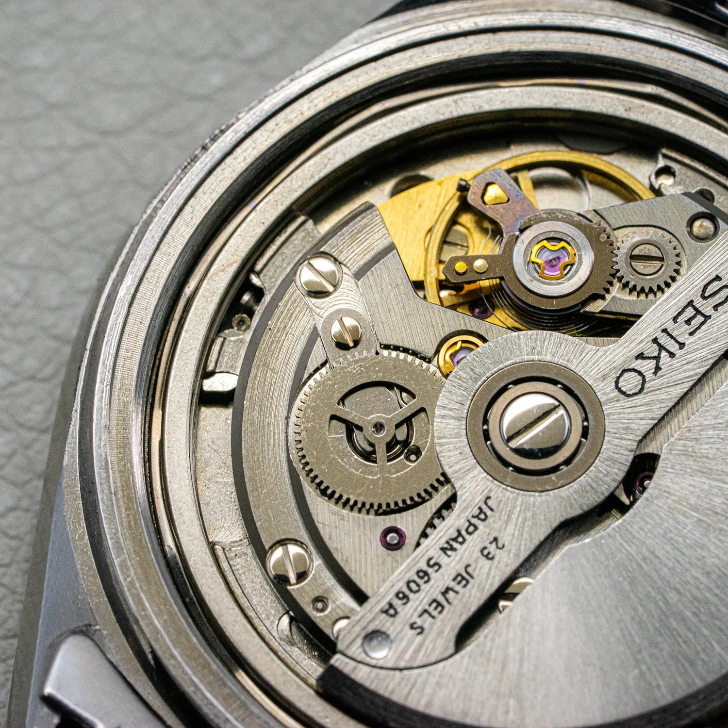 Close-up of a Seiko 5606 watch mechanism on a gray background