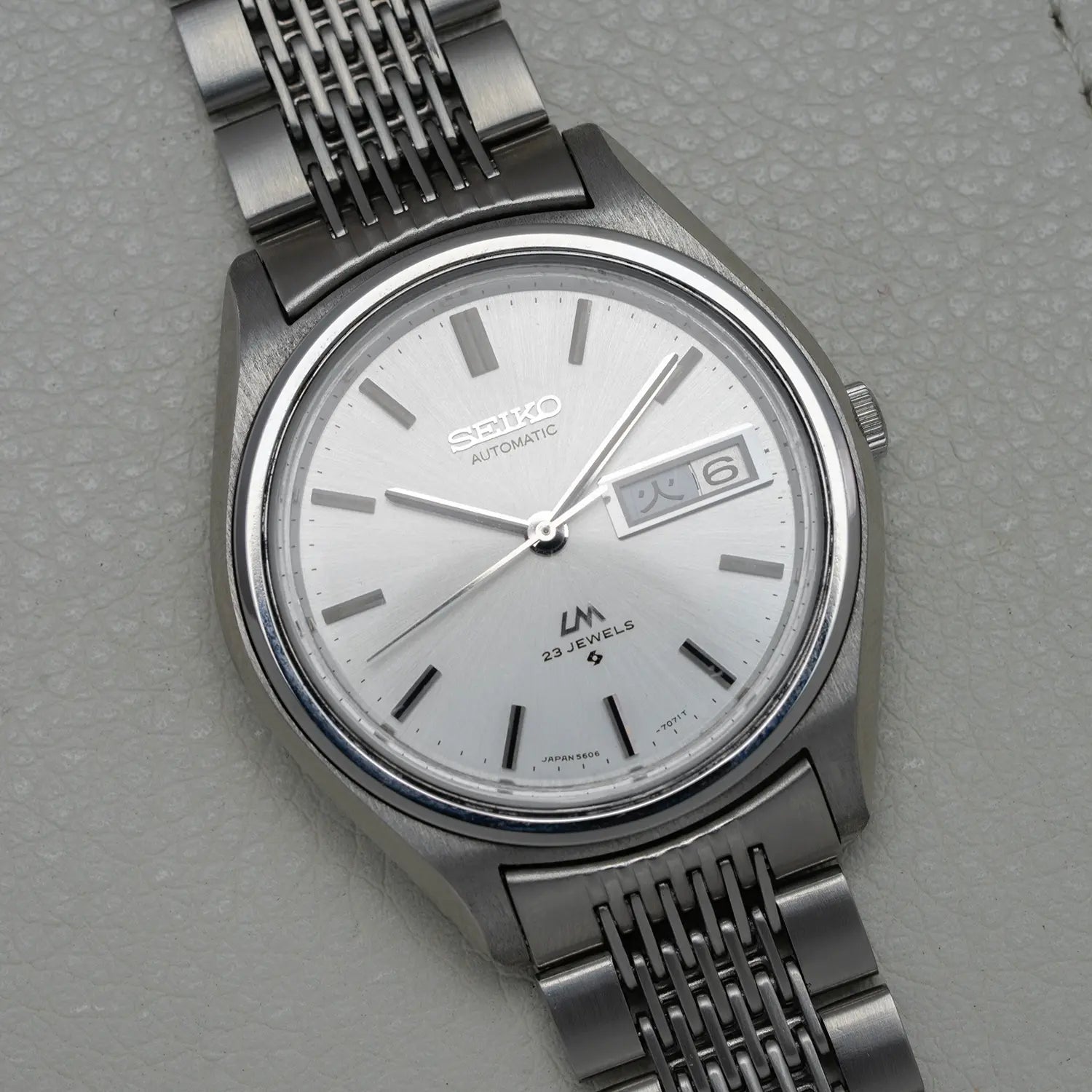 Silver Seiko LM 5606-7071 watch on a gray background
