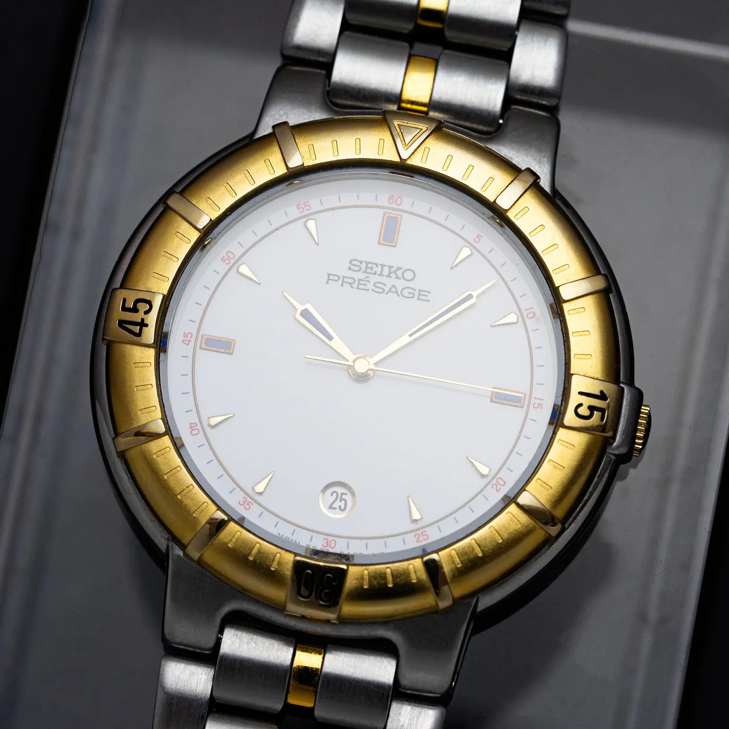 Seiko Presage 5E32 6A00 watch with gold and silver band on a gray background