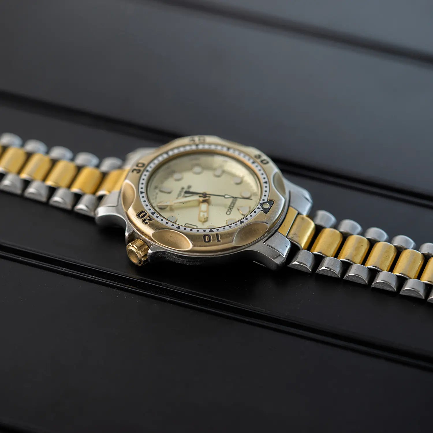 Two-tone watch Seiko Scuba 200M, Ref. 5H25-6000 with yesllow crown with gold and silver band on a black surface