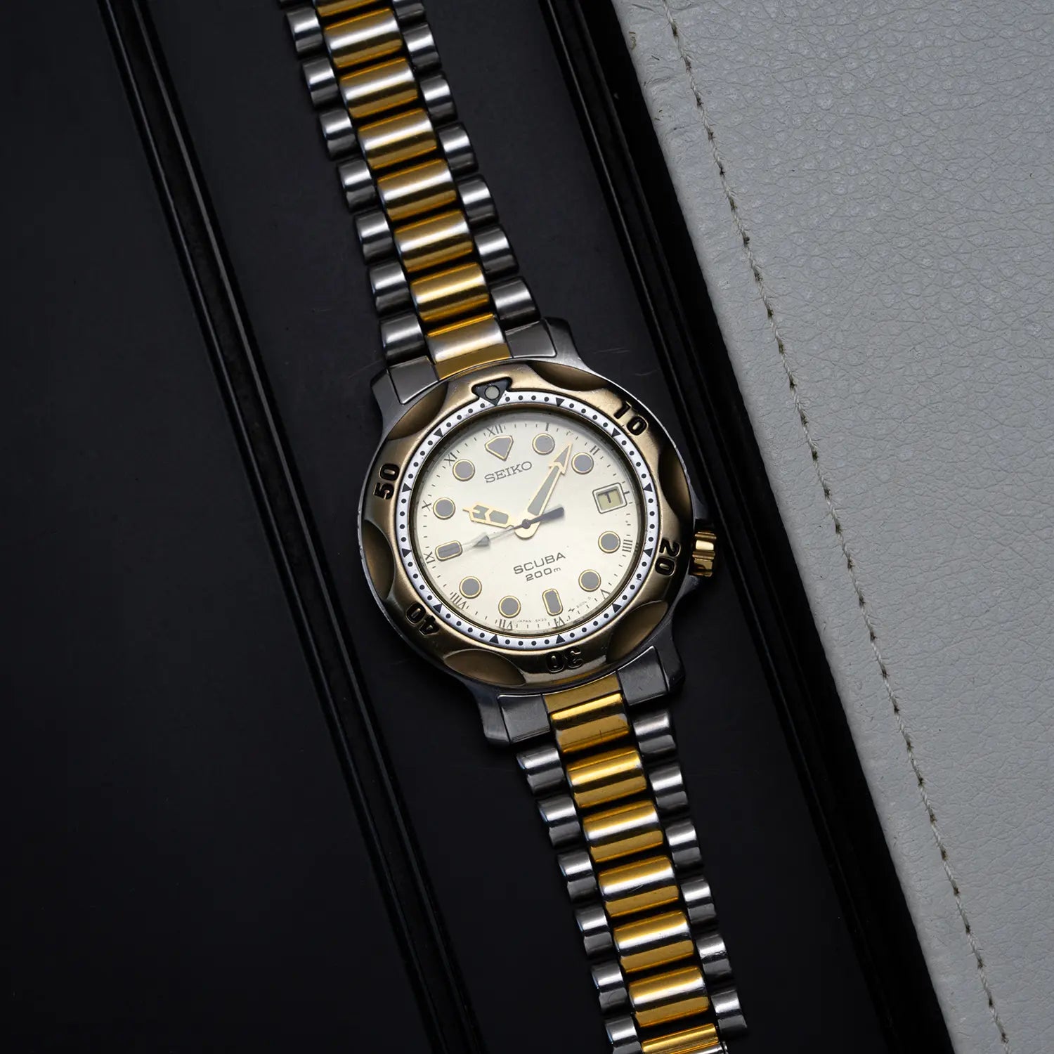 Seiko Scuba 200M, Ref. 5H25-6000 with gold and silver bracelet on a dark surface