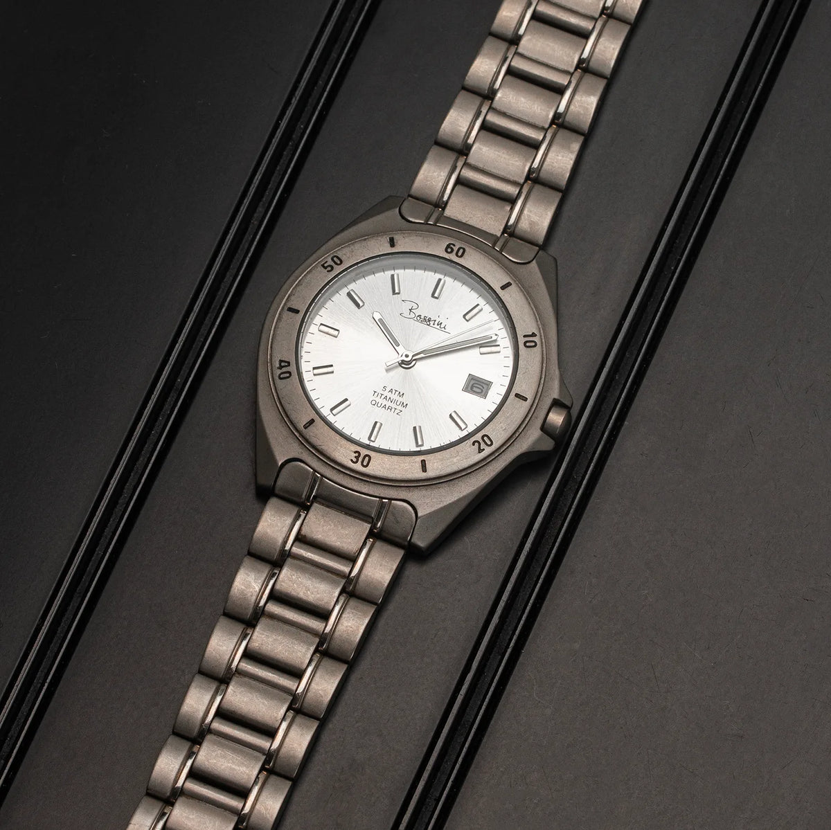 A Bossini Titanium watch with a silver-toned and link bracelet, featuring a white dial with black markings and a date window.