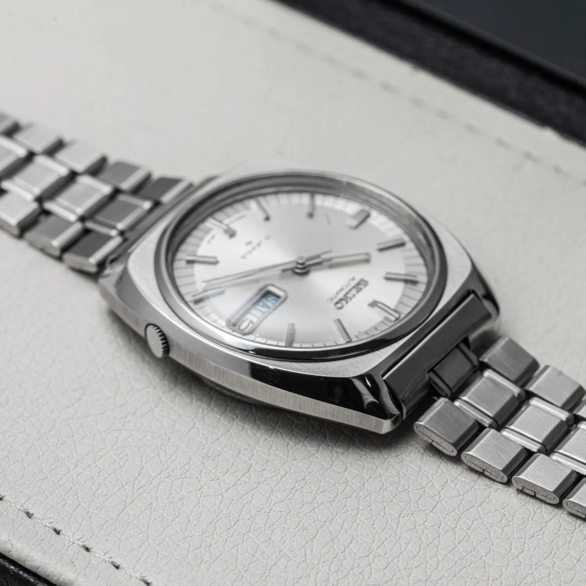 A close-up shot of a Seiko, Ref. 7009-8100, Cal. 7009, Men’s Automatic, 1977 wristwatch with a silver stainless steel case and link bracelet, featuring a white dial with a date window.