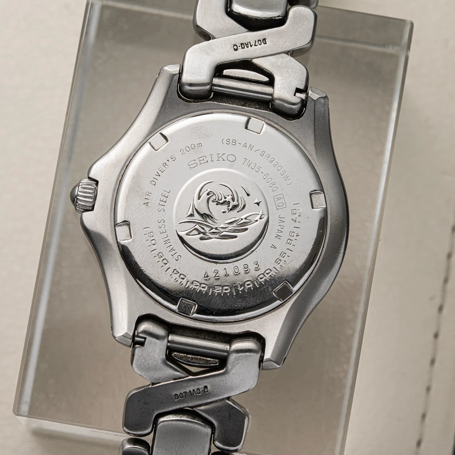 Close-up of the back of a stainless steel Seiko Scuba wristwatch mounted on a clear display stand, showing engraved branding and model details.